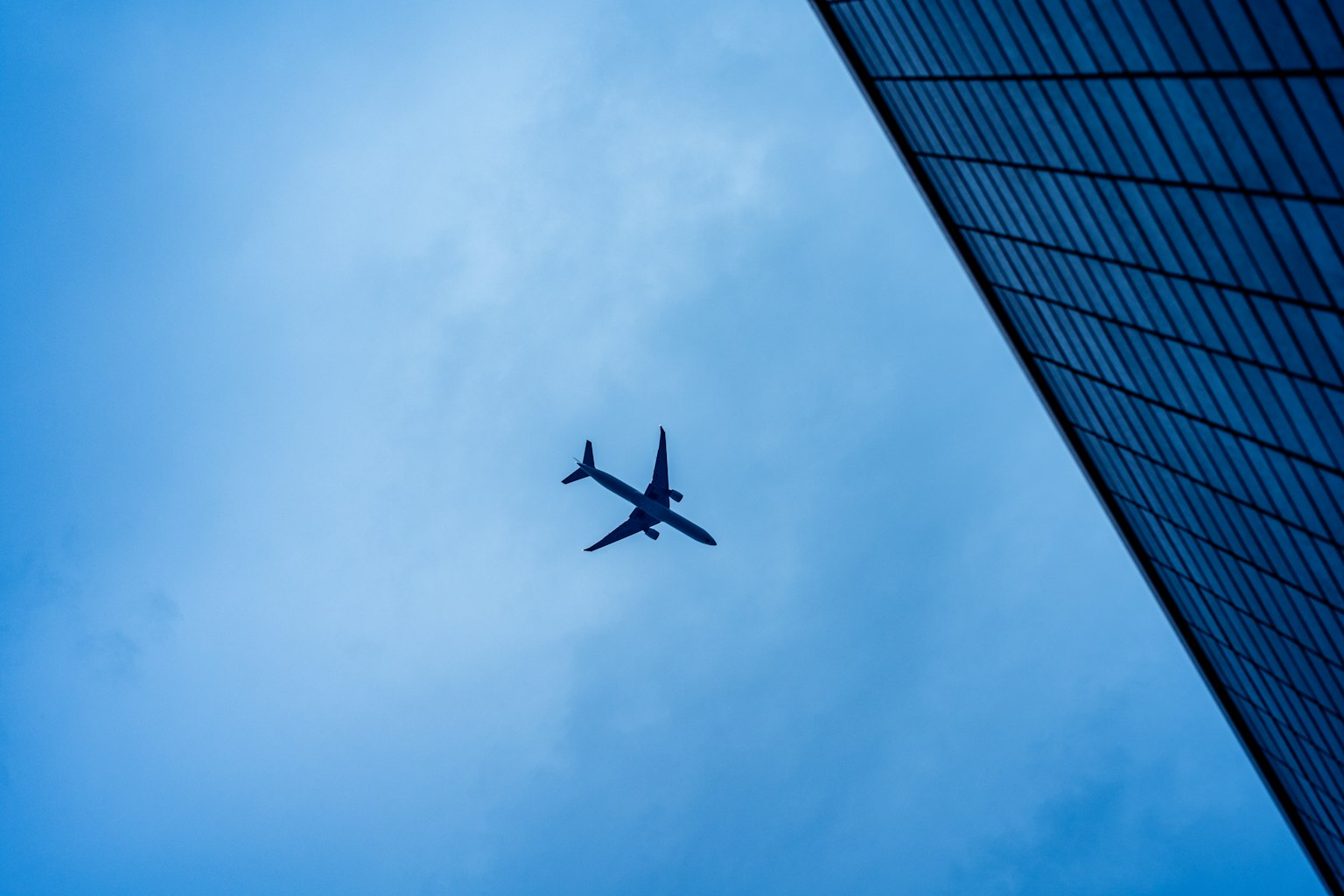 Aereo che vola contro un cielo blu con un bordo di edificio