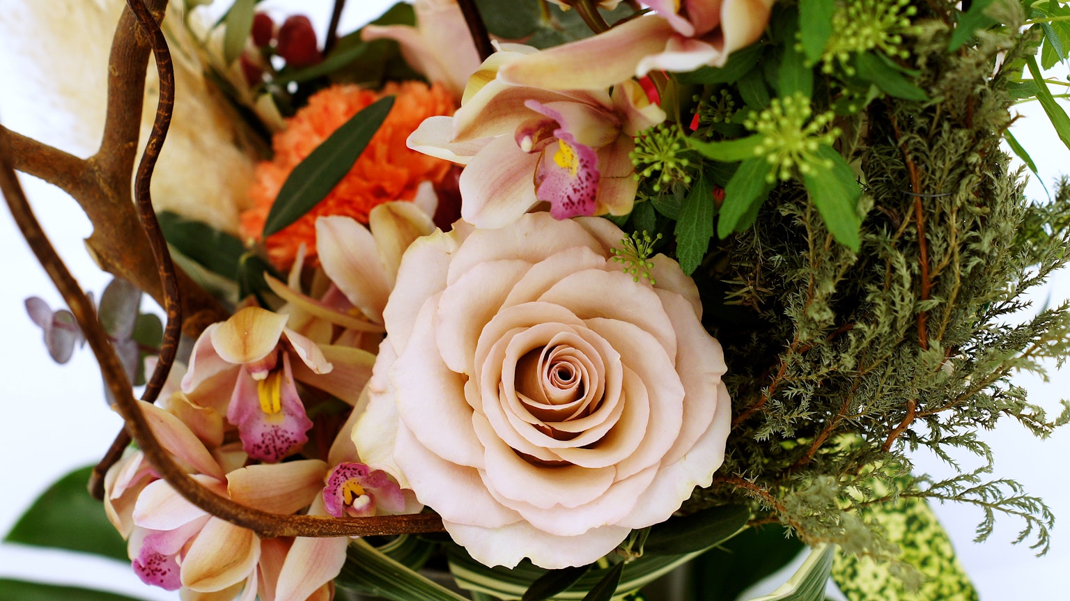 Nahaufnahme eines schönen Straußes mit einer rosa Rose und Orchideen, grünem Laub und feinen Details