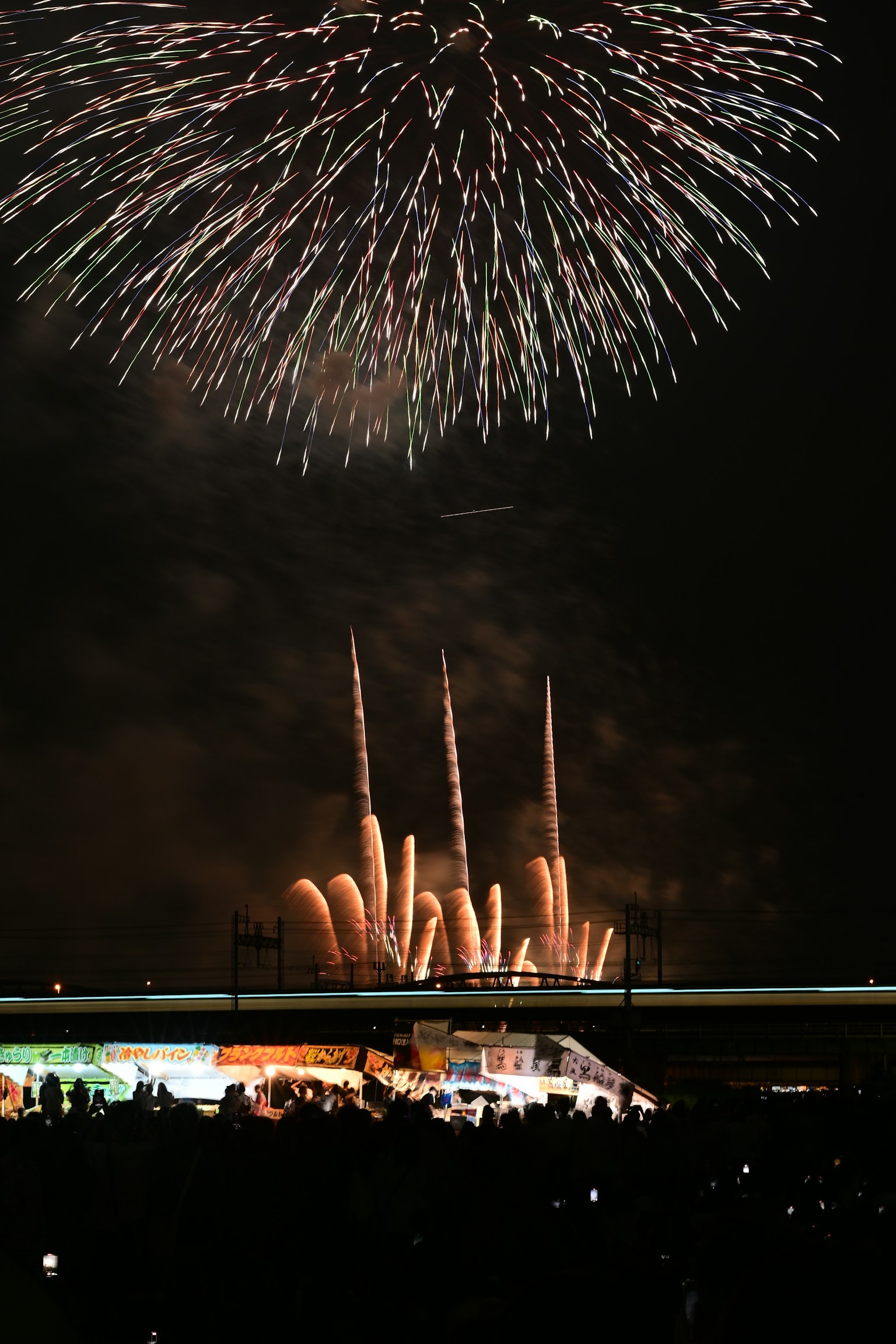 Feux d'artifice colorés illuminant le ciel nocturne avec des silhouettes de spectateurs