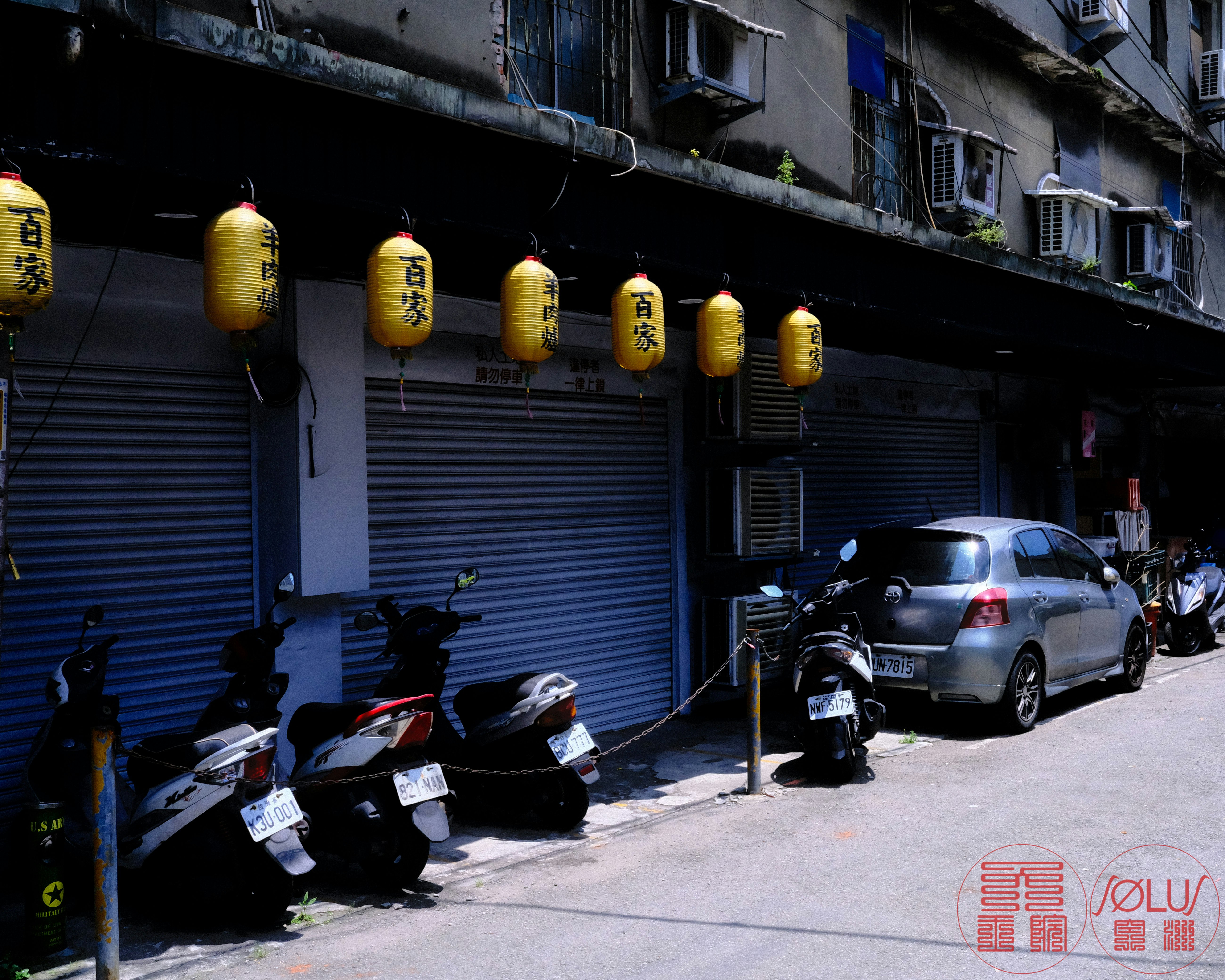 台北の路地に並ぶバイクと提灯のある店先