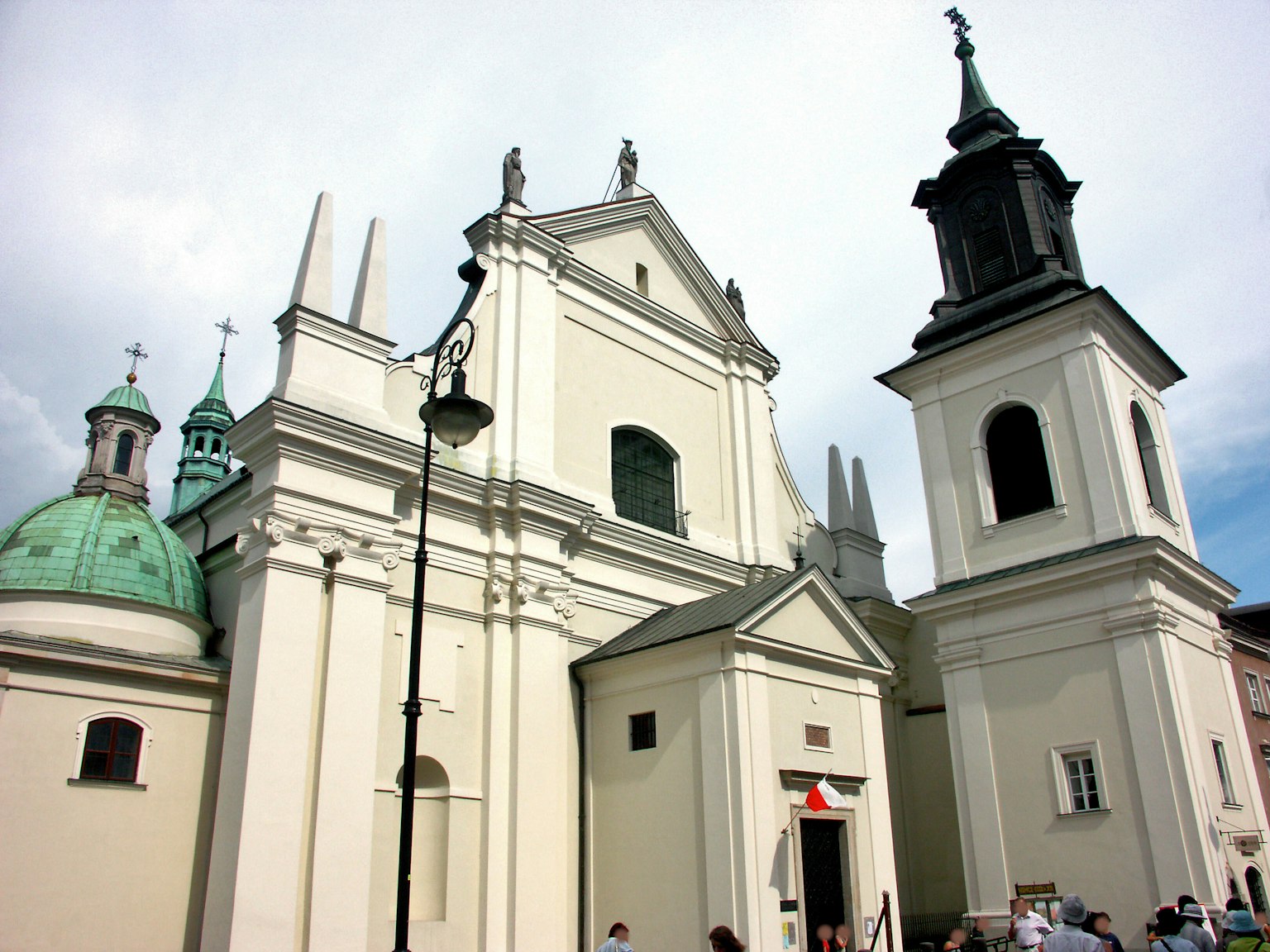 Extérieur d'une église blanche avec des dômes verts et un grand clocher