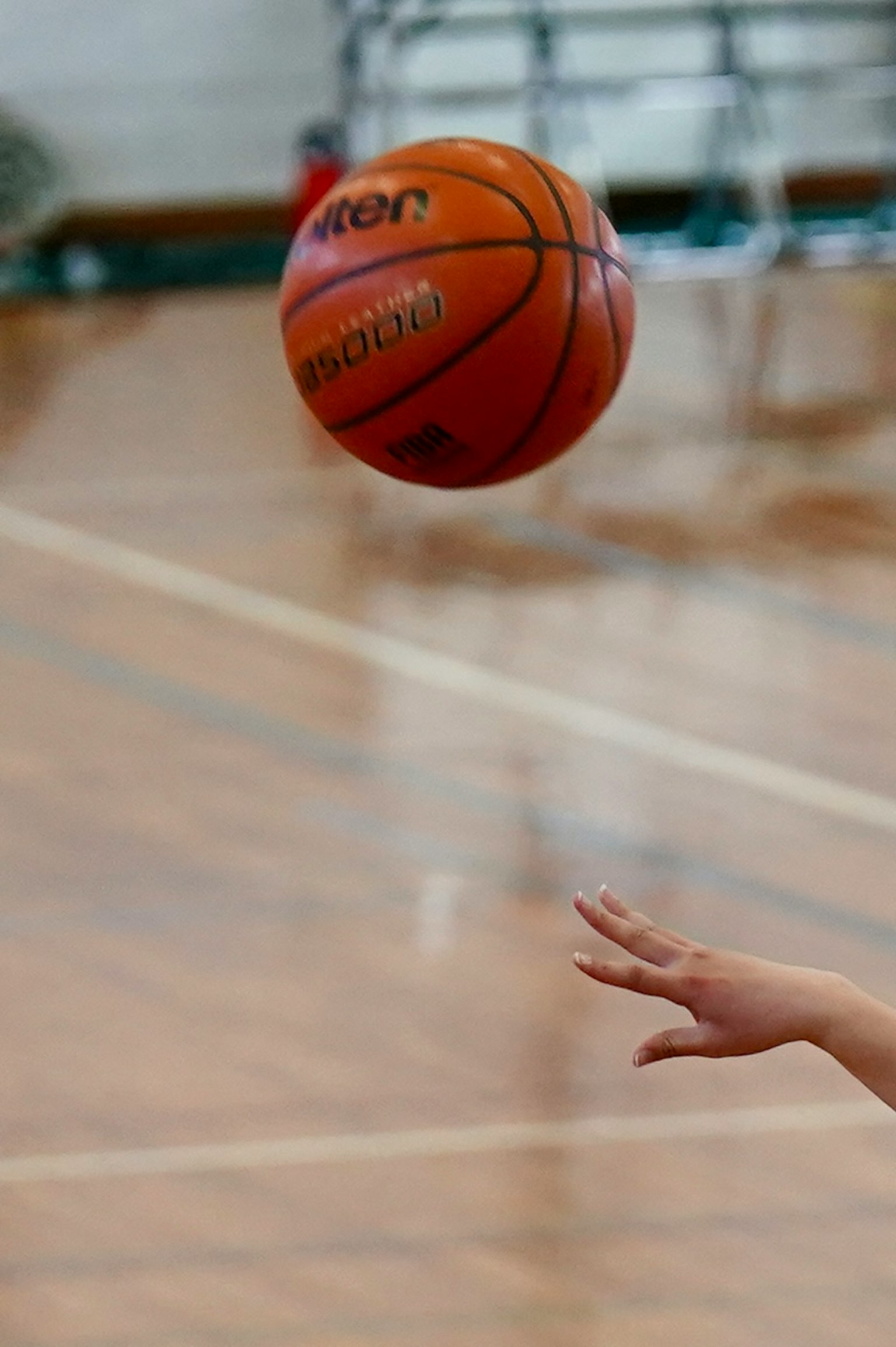 Sebuah bola basket yang mengapung di udara dengan tangan yang meraihnya