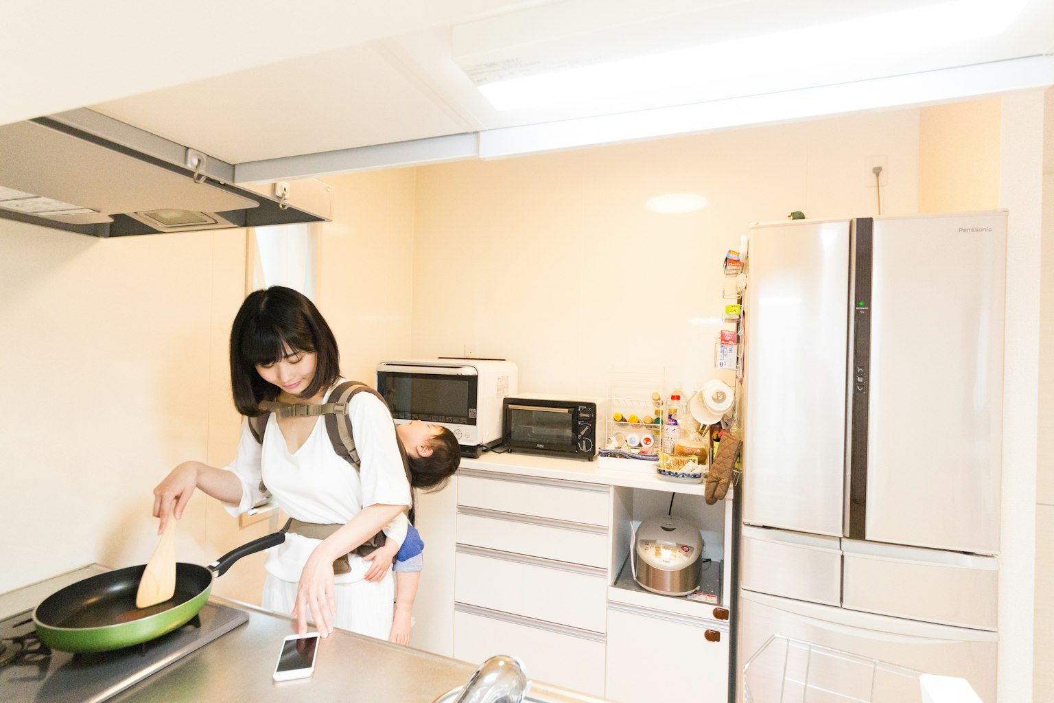 Una mujer cocinando en una cocina con una sartén y un refrigerador visibles