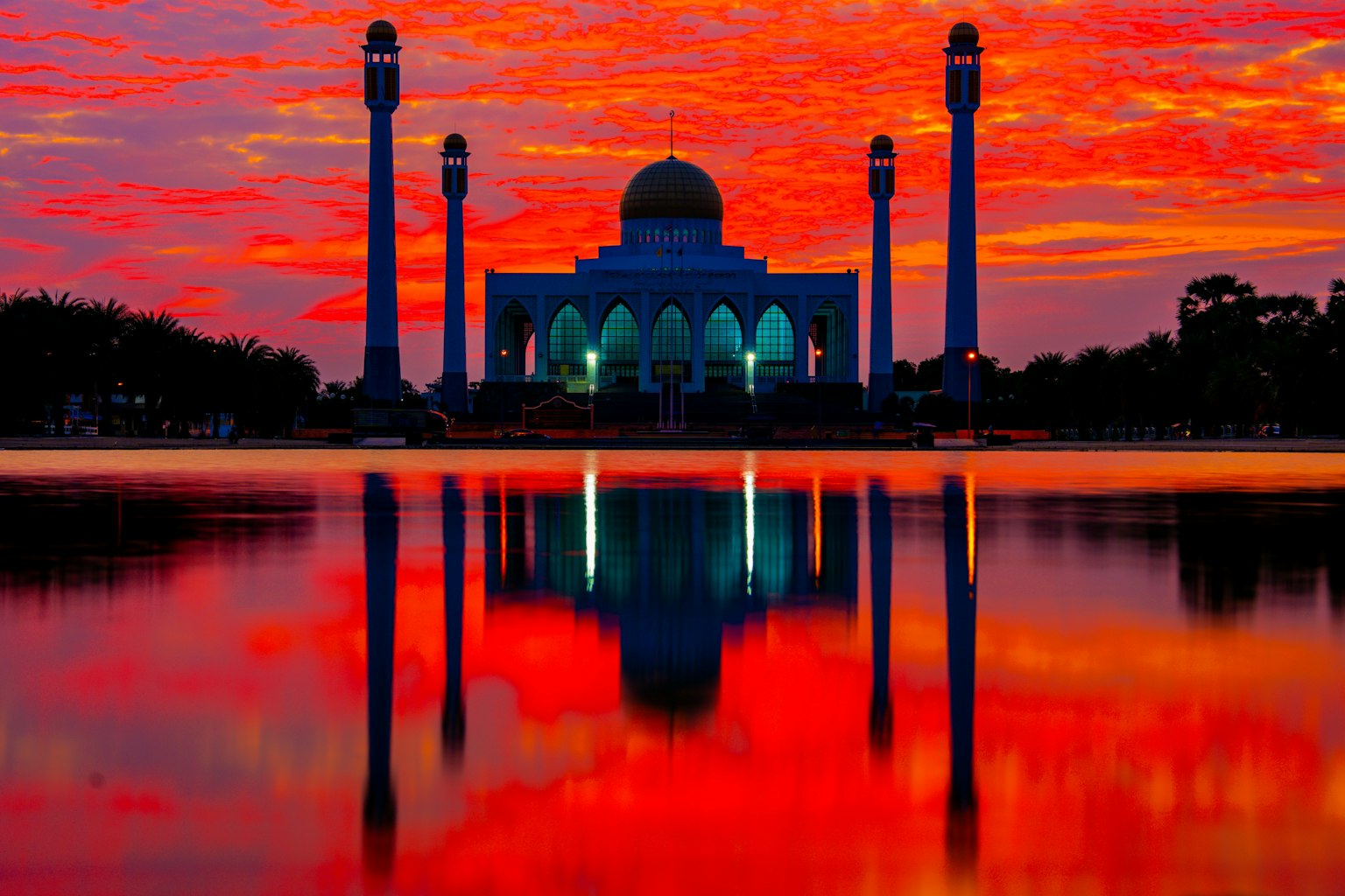 Una moschea silhouettata contro un vivace tramonto con riflessi nell'acqua
