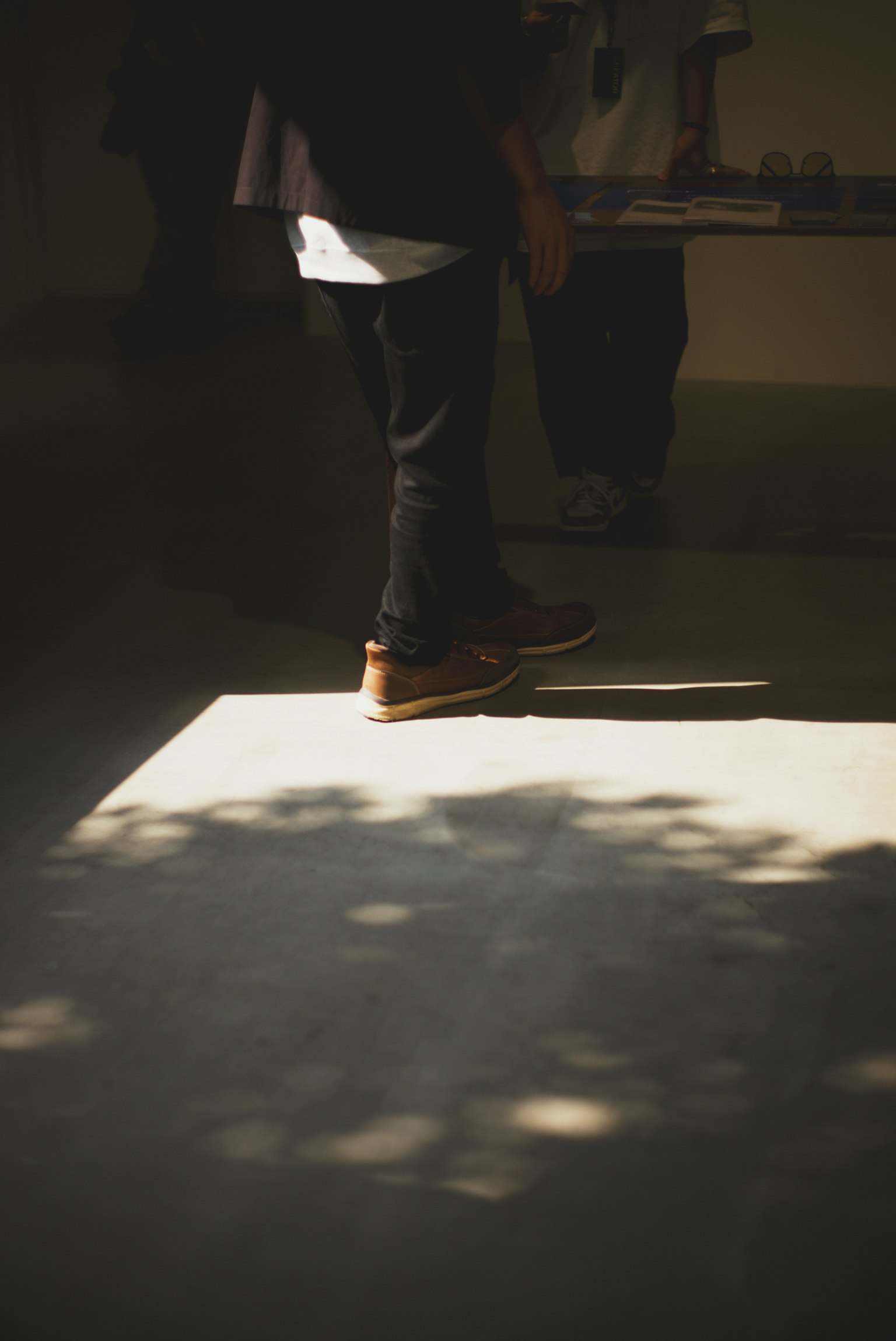 Los pies de una persona de pie en la sombra con reflejo de luz