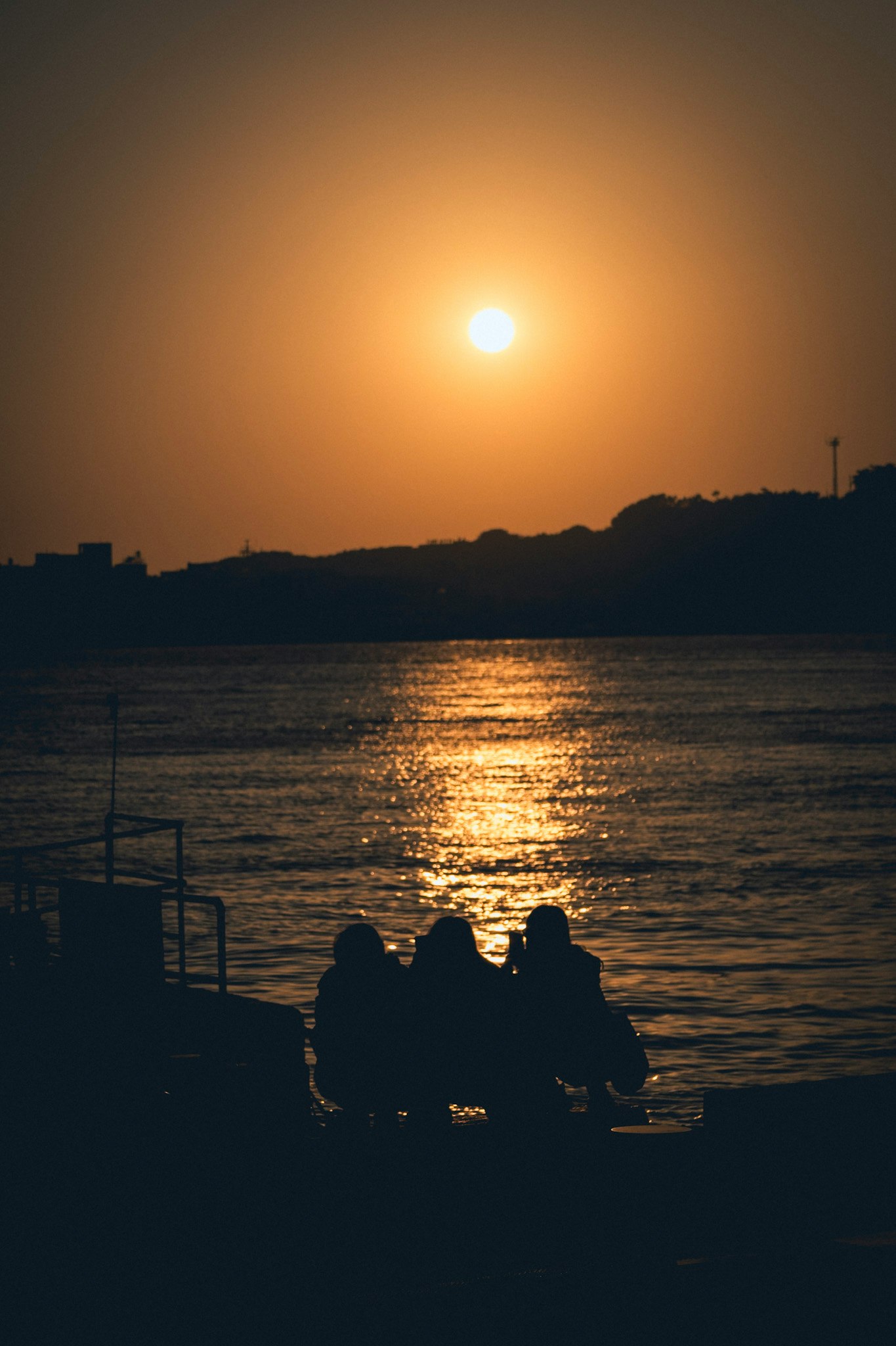 夕暮れの海面に沈む夕日と小舟のシルエット