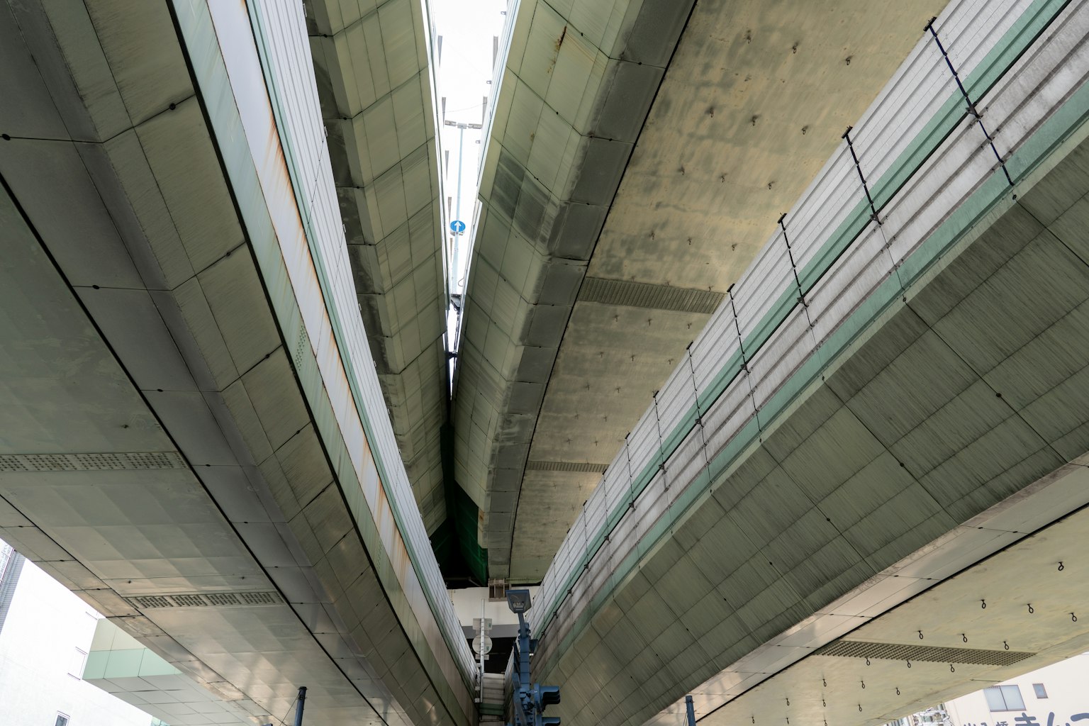 Pemandangan dari bawah jembatan beton yang menampilkan desain arsitektur linier