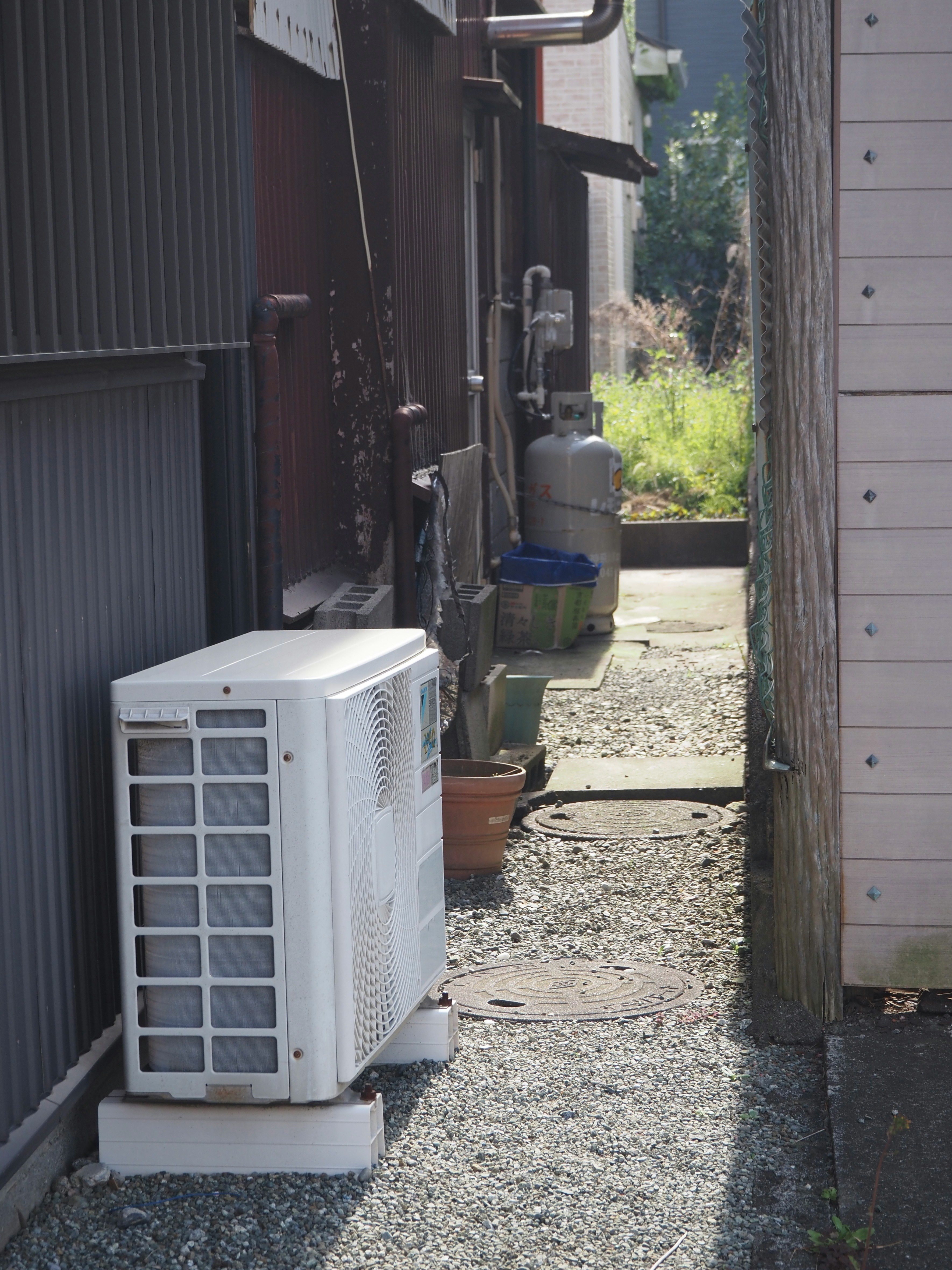 路地の物置と屋外設置のエアコン室外機