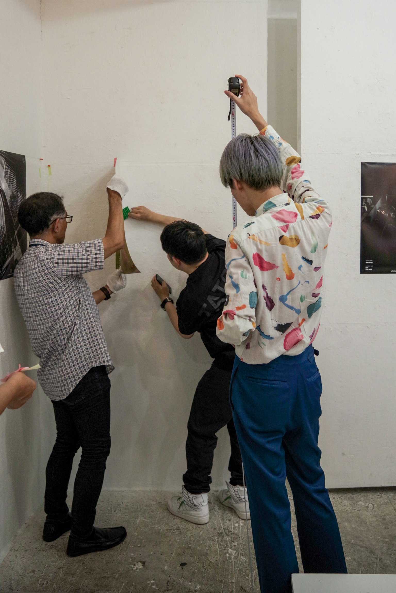 Artists installing artwork on a wall in a gallery setting