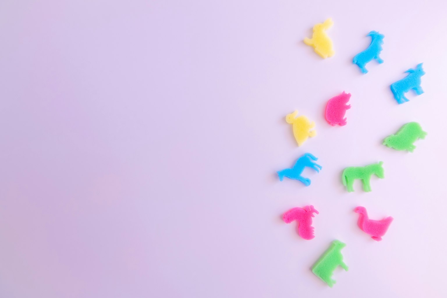 Jouets en plastique colorés en forme d'animaux éparpillés sur un fond violet