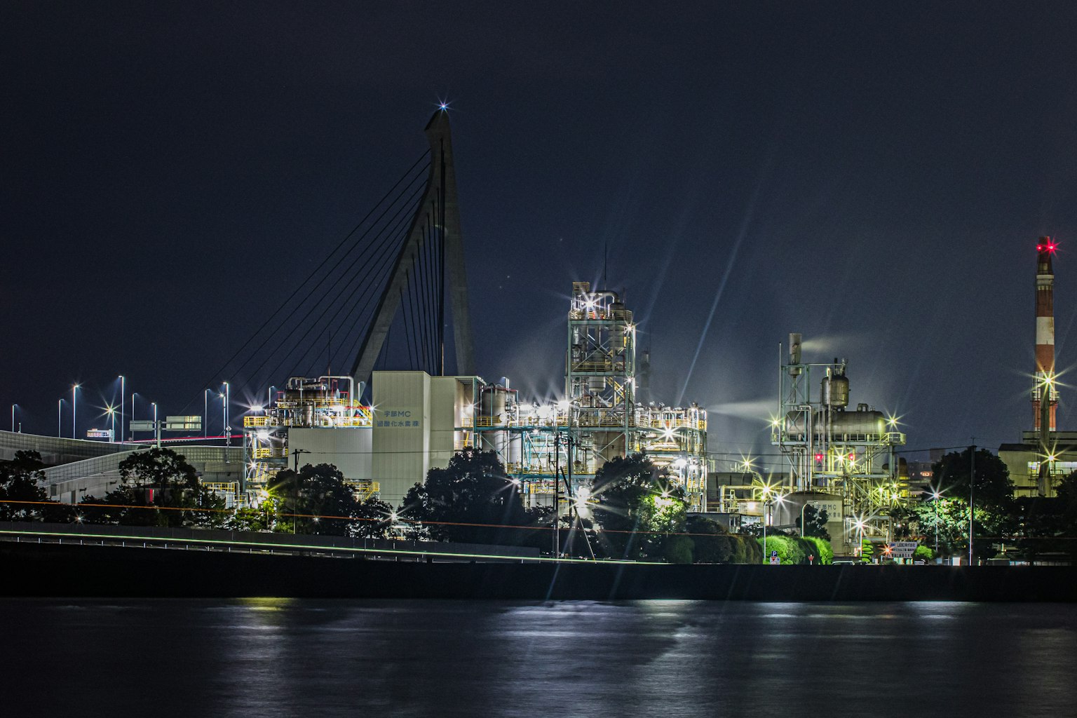 Complexe industriel illuminé la nuit se reflétant sur l'eau