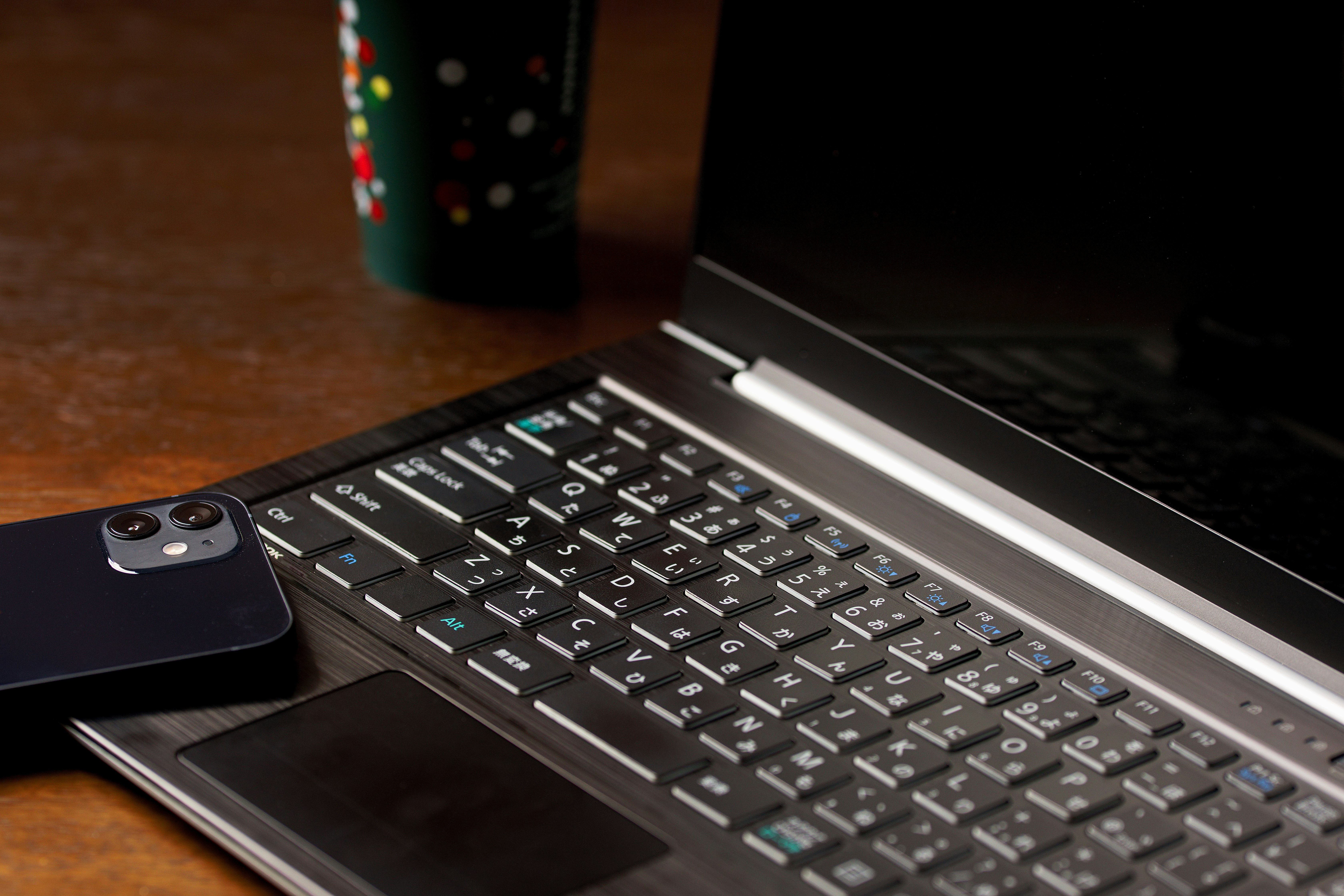 デスク上のノートPCとスマホ、コーヒーのある作業風景