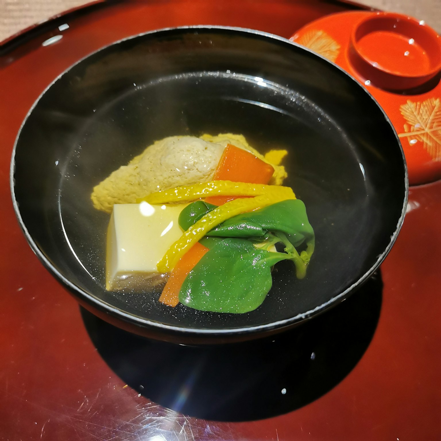 Soupe chaude de légumes et de tofu servie dans un bol noir