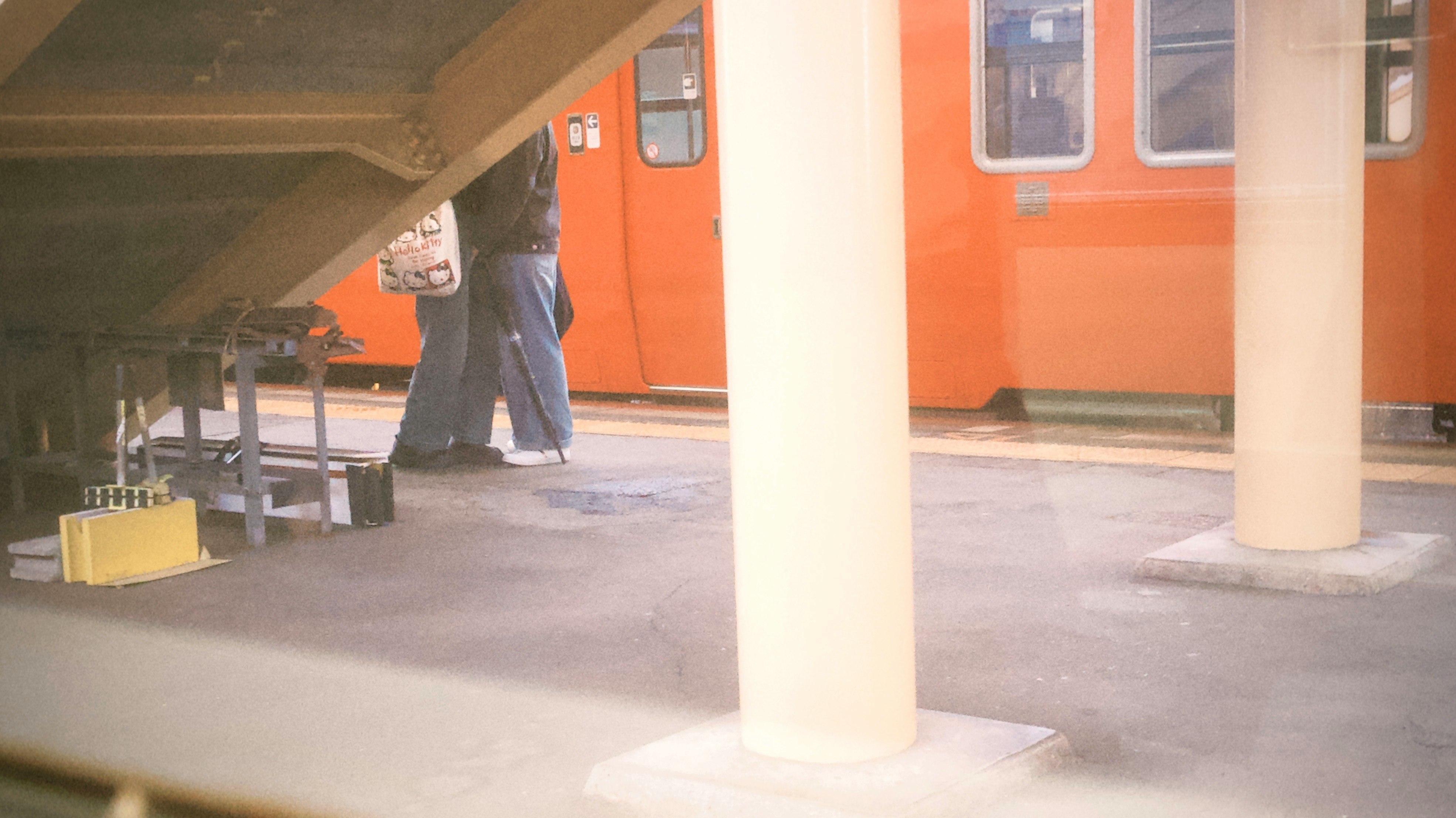 駅のホームで電車の脇を歩く人