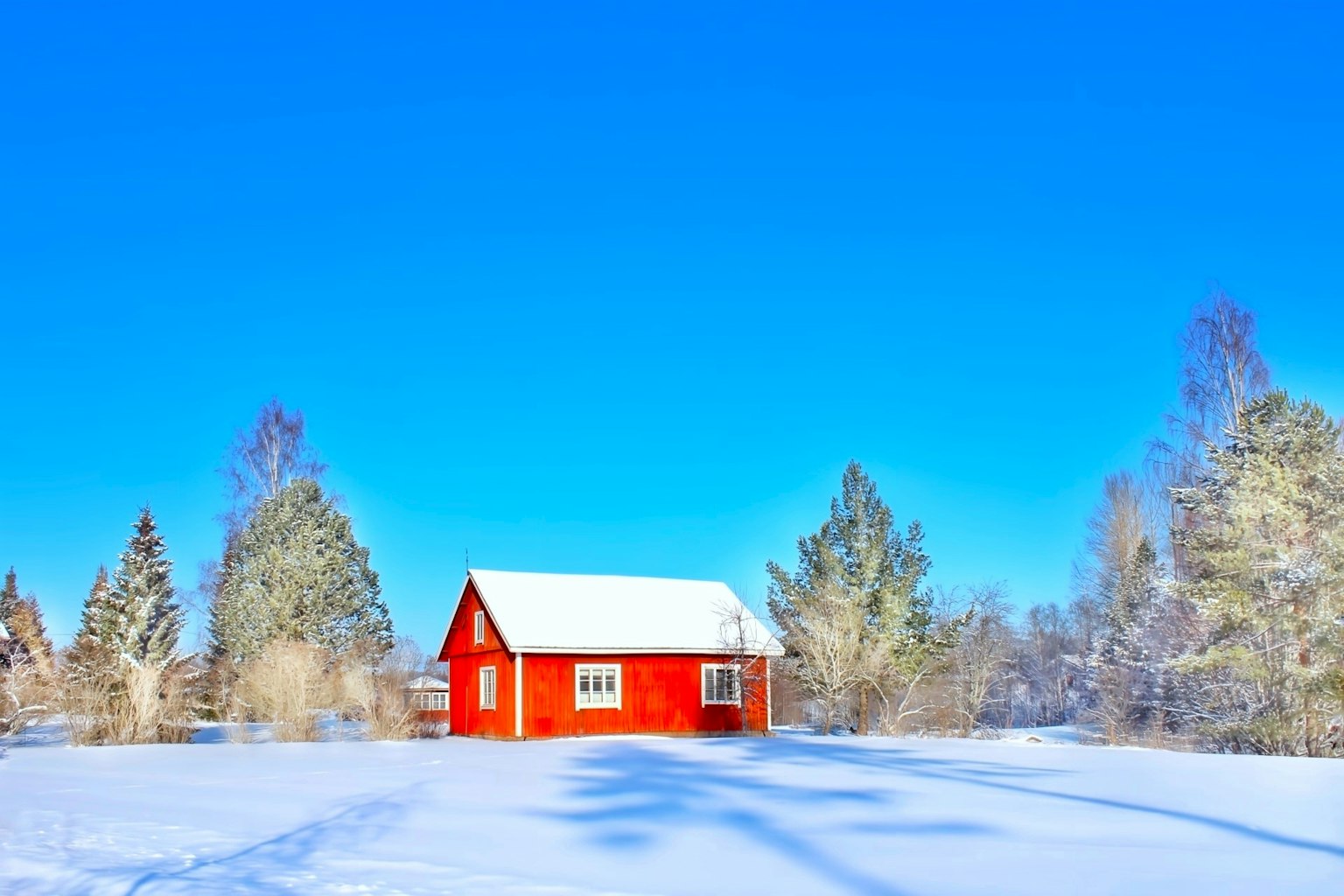 被雪覆蓋的紅色小屋和晴朗的藍天