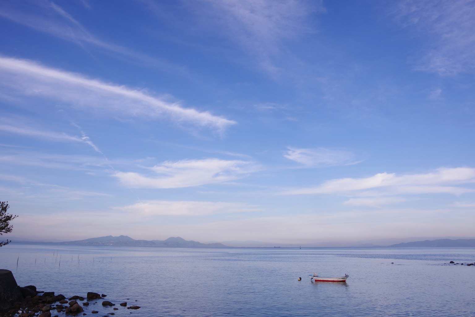 A serene view of a small boat floating on calm water under a blue sky