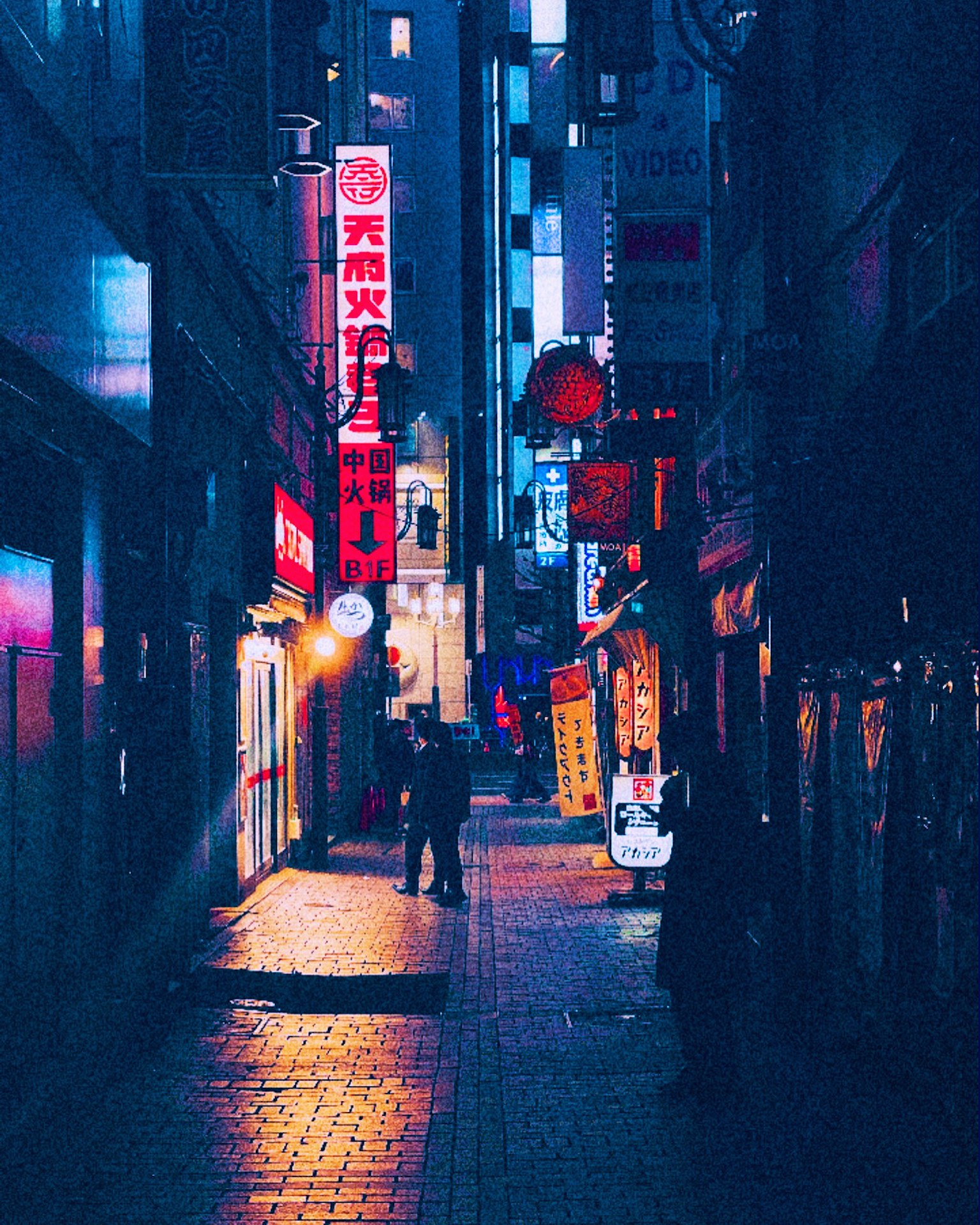 夜の街並みにある狭い路地とネオンの看板