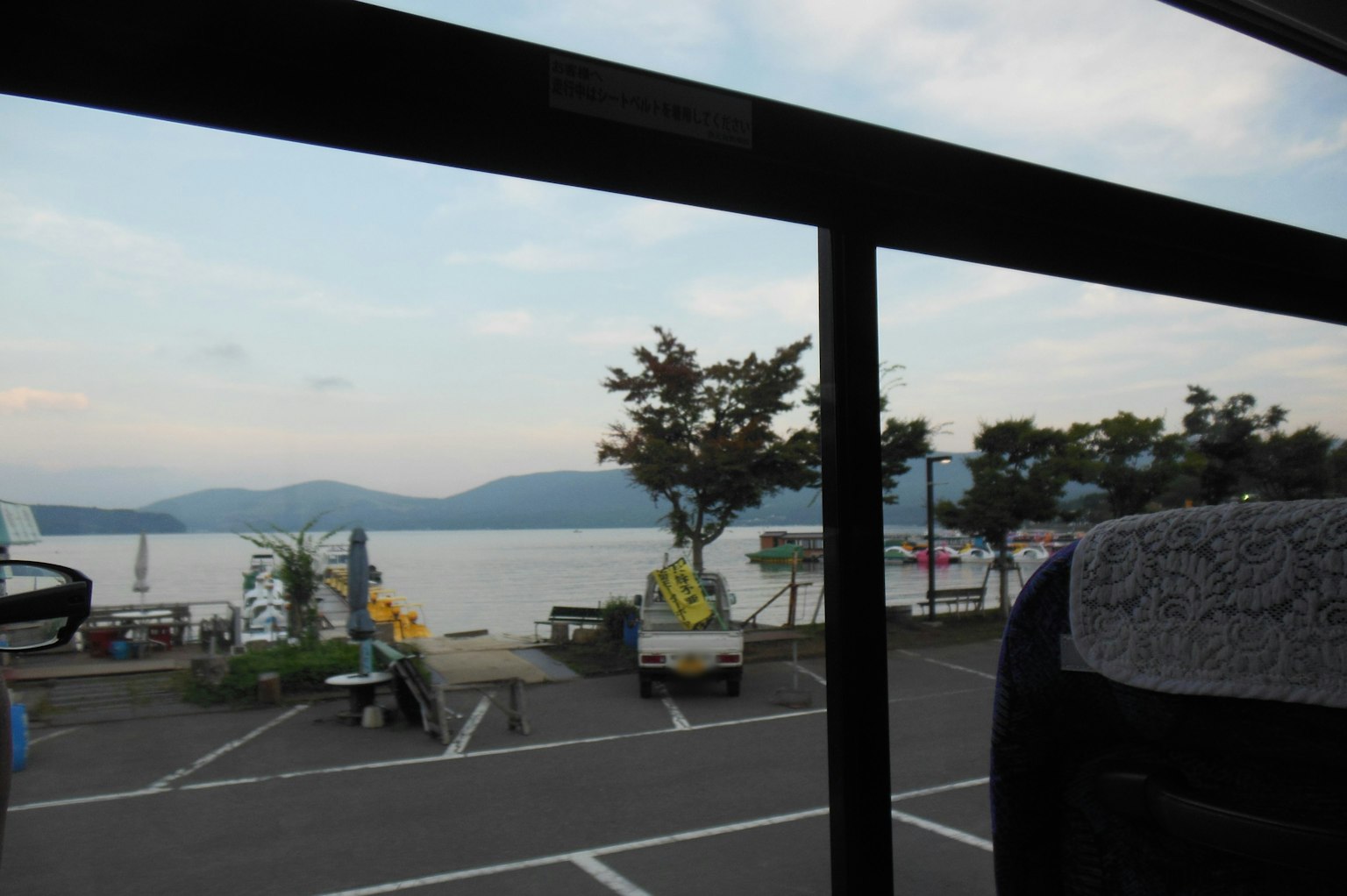 Vista di un lago e montagne attraverso il finestrino di un autobus barche parcheggiate nelle vicinanze