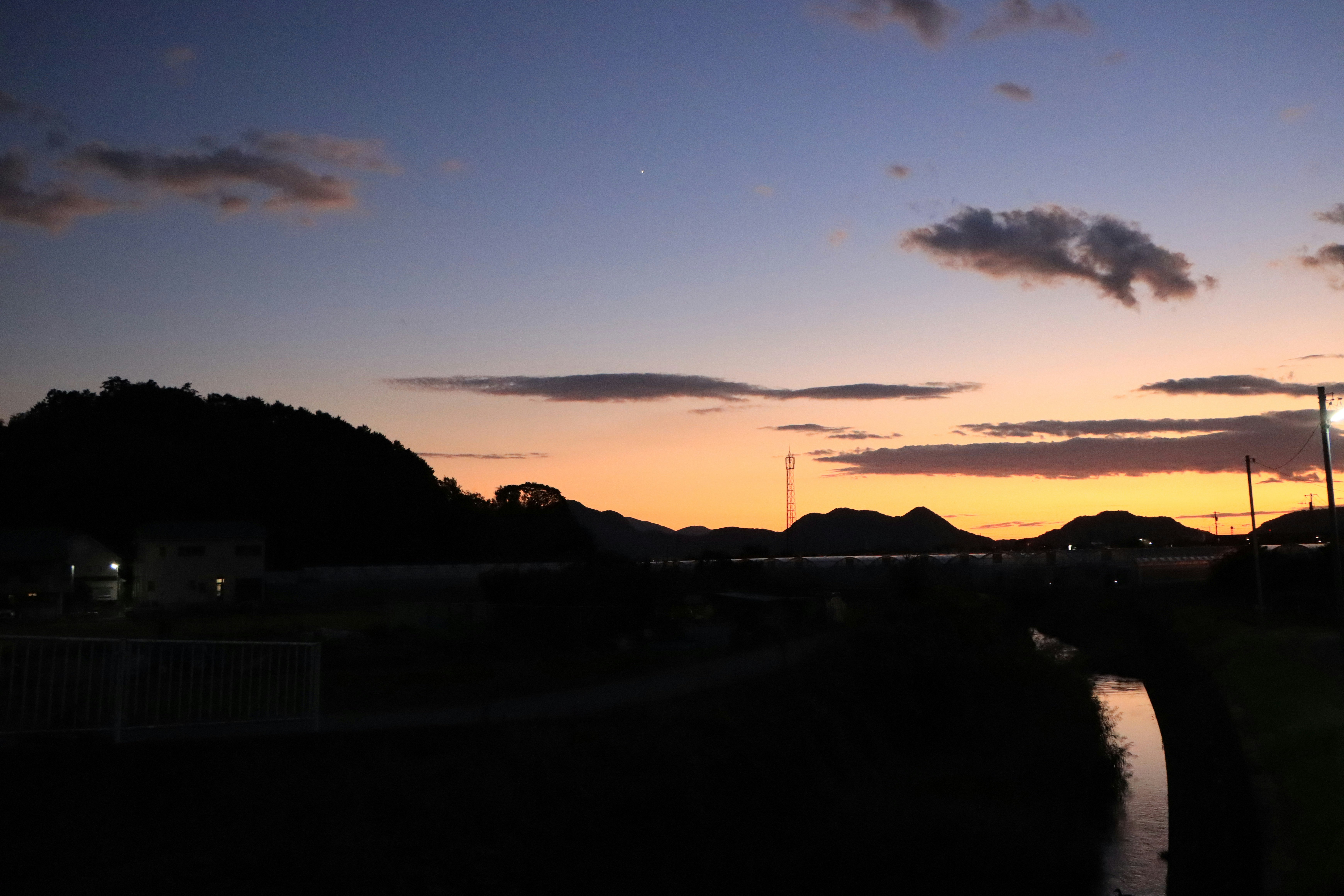 dusk riverside embankment with silhouetted hills