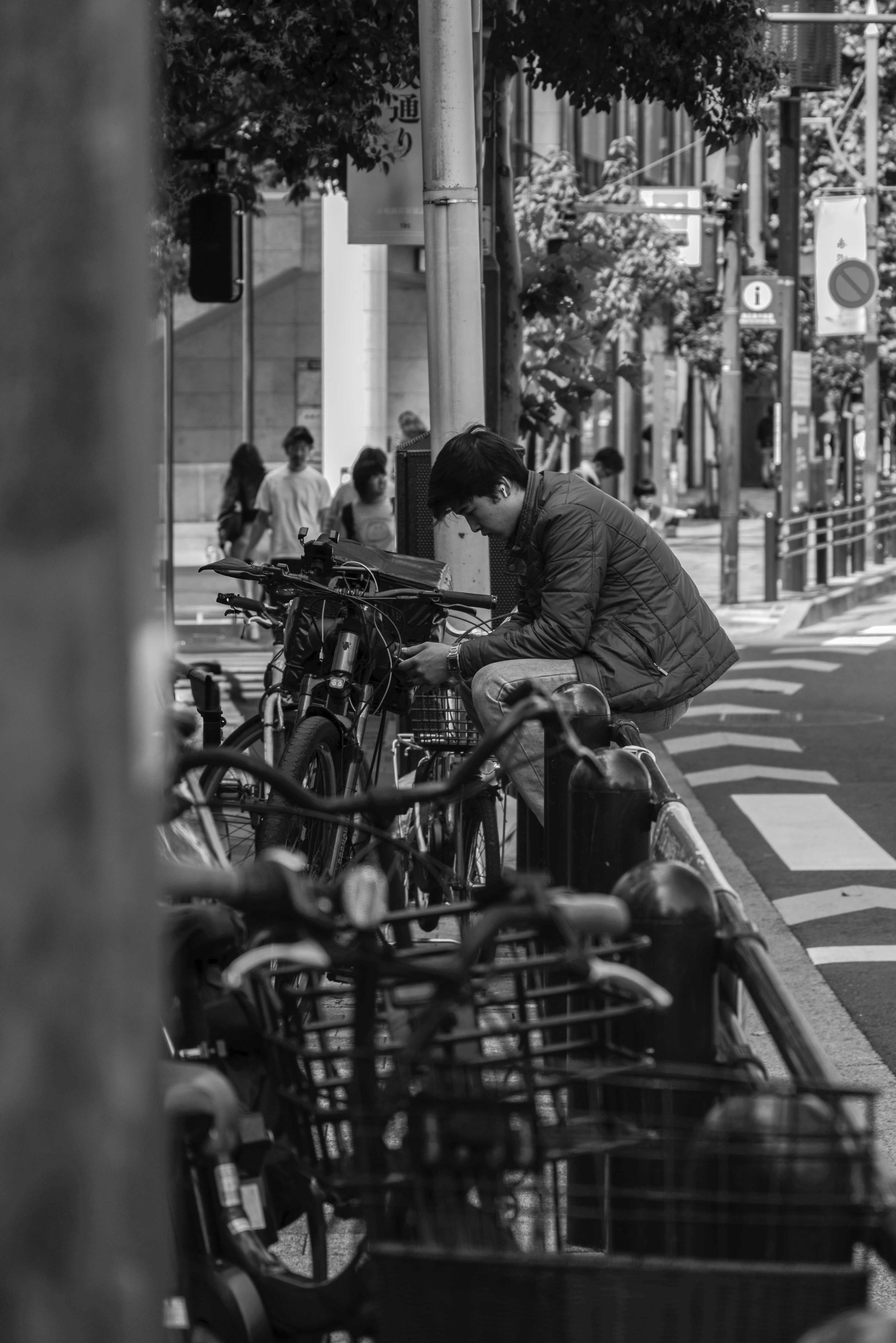 路地の横断歩道で自転車と配達待ちの人々