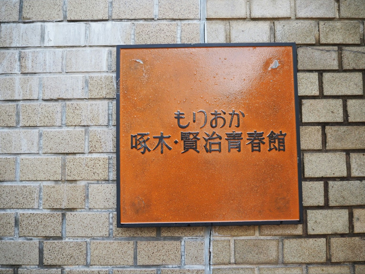 橙色標誌上有日文文本，貼在磚牆上