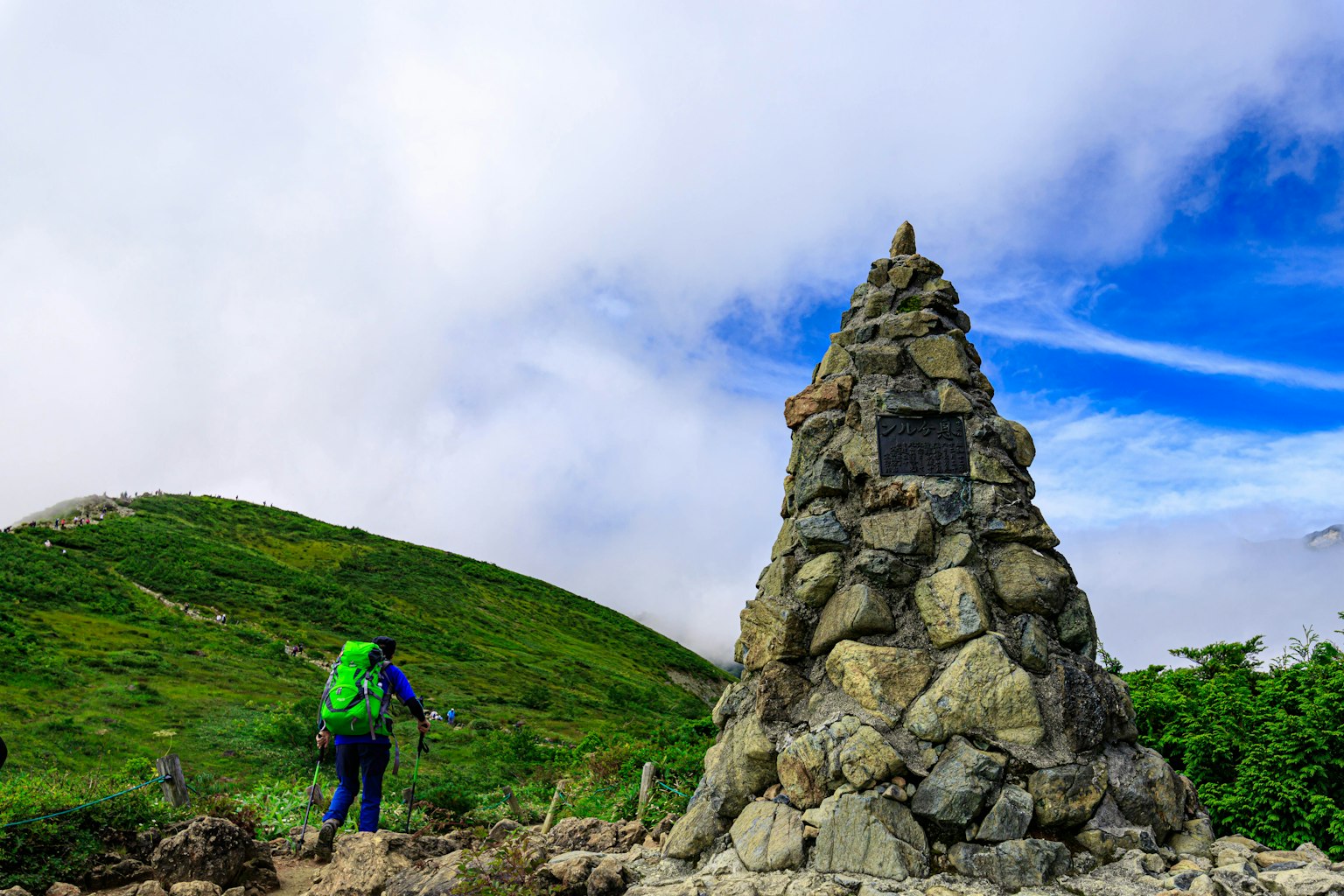 登山者在綠意盎然的風景中走在石碑旁