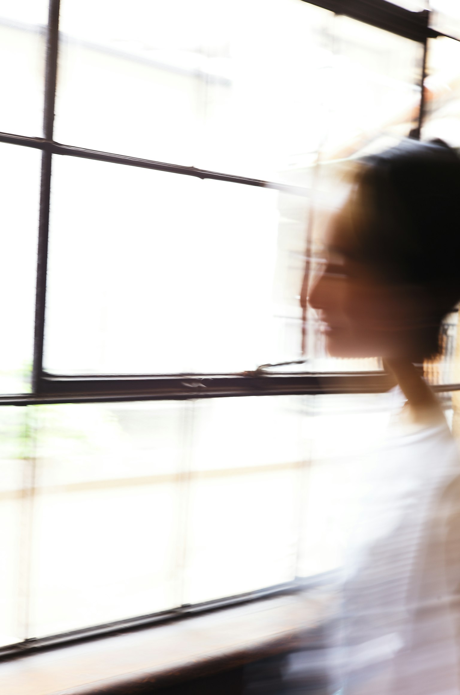 Verschommene Silhouette einer Frau, die sich in der Nähe eines Fensters bewegt