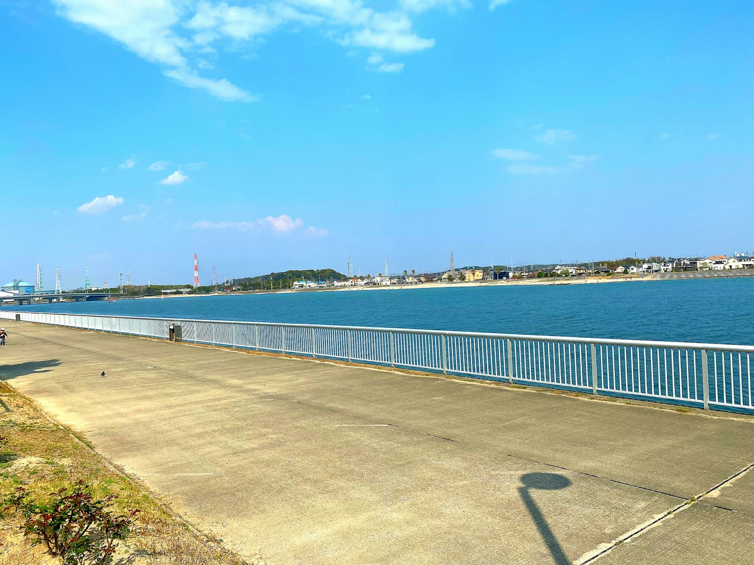 Pemandangan pantai dengan laut biru dan langit trotoar yang paving dan pagar putih