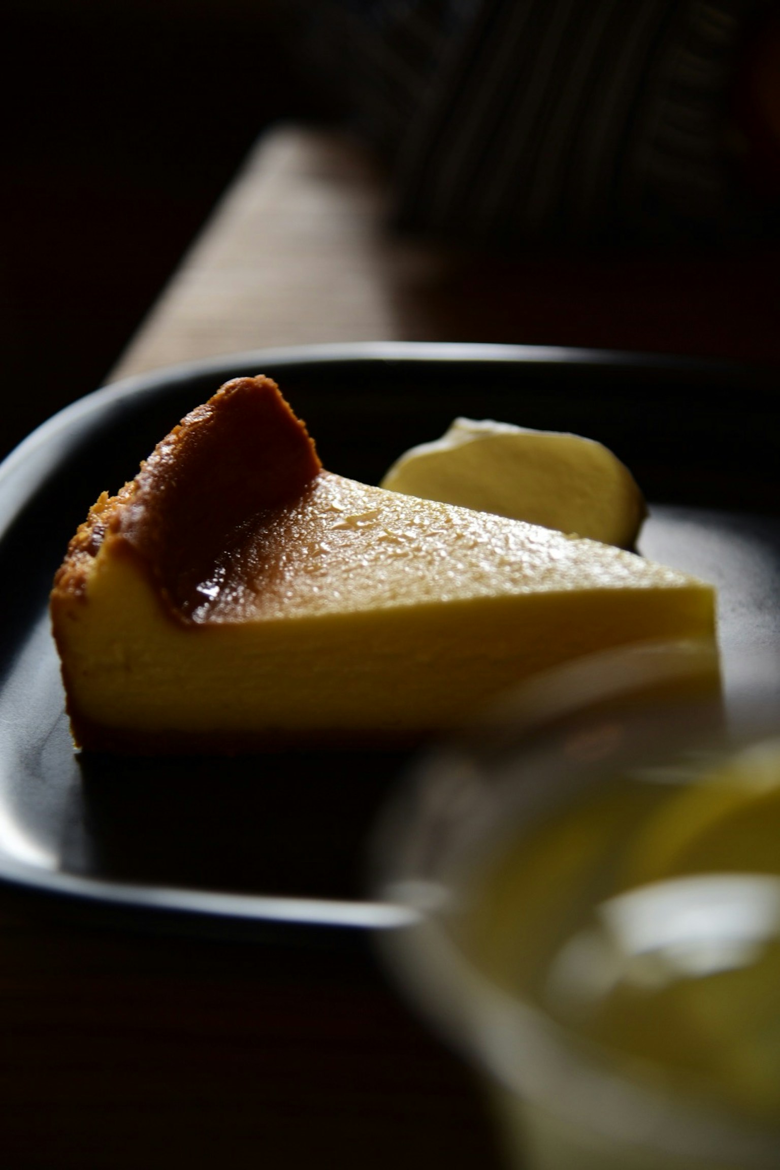黒い皿の上に置かれたスライスされたチーズケーキとバター