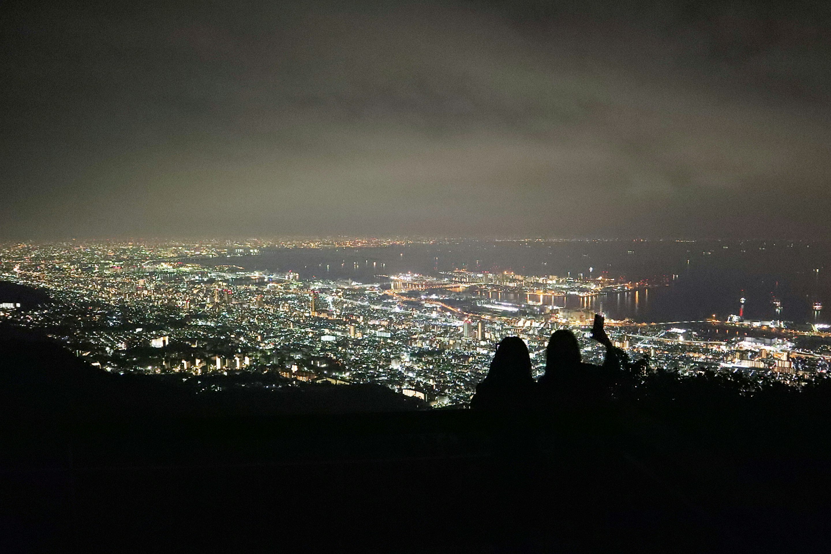 六甲山の夜景を見下ろす山頂のシルエット