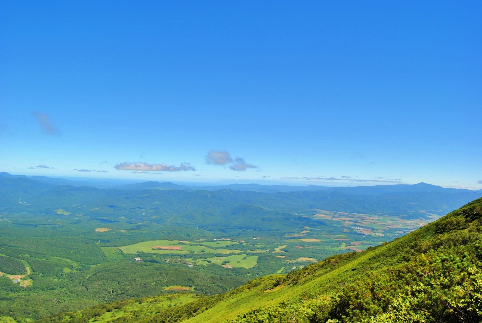 Paisaje montañoso con colinas verdes y cielo azul claro