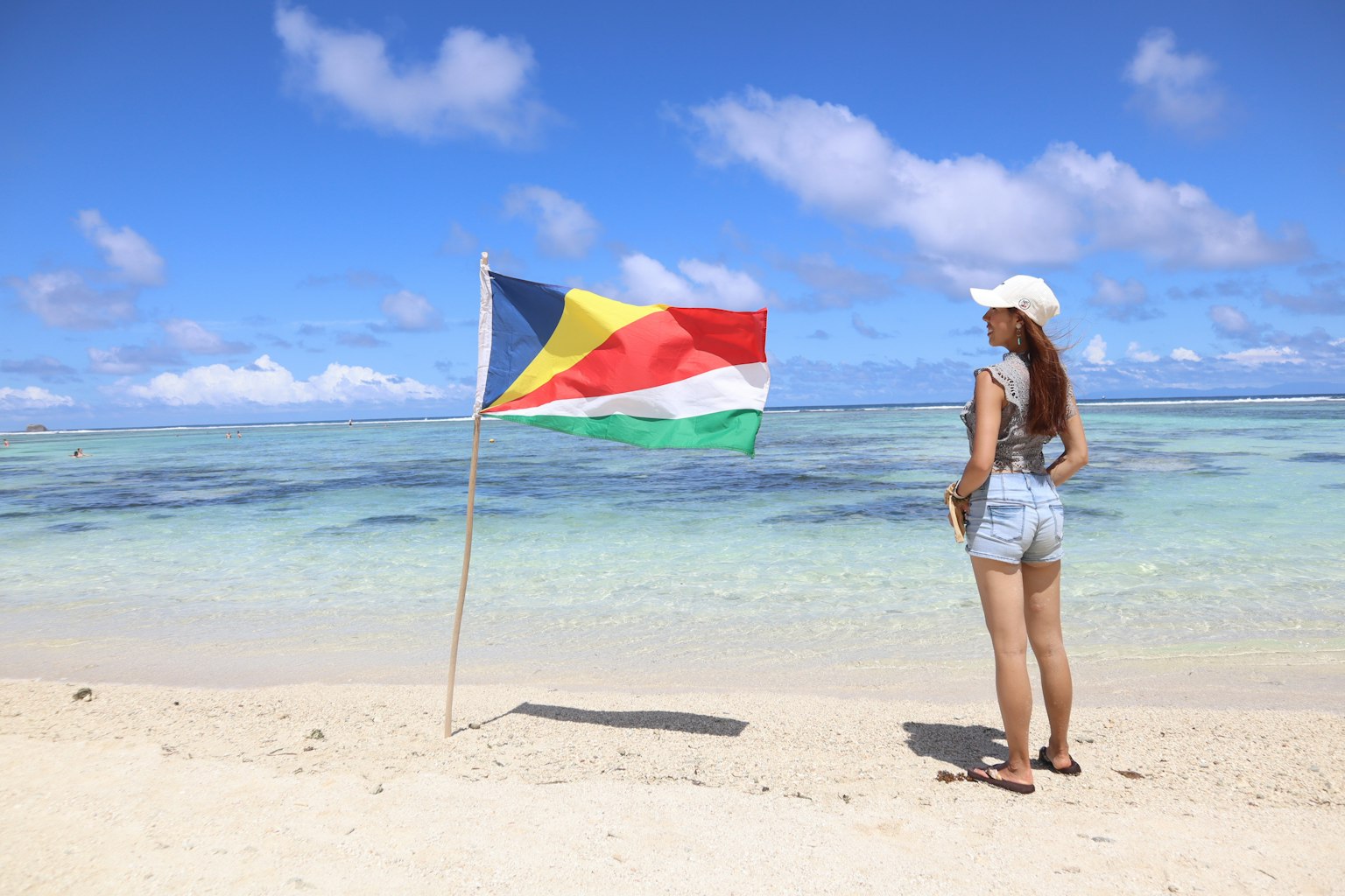 Người phụ nữ đứng trên bãi biển với cờ Seychelles bay trong gió