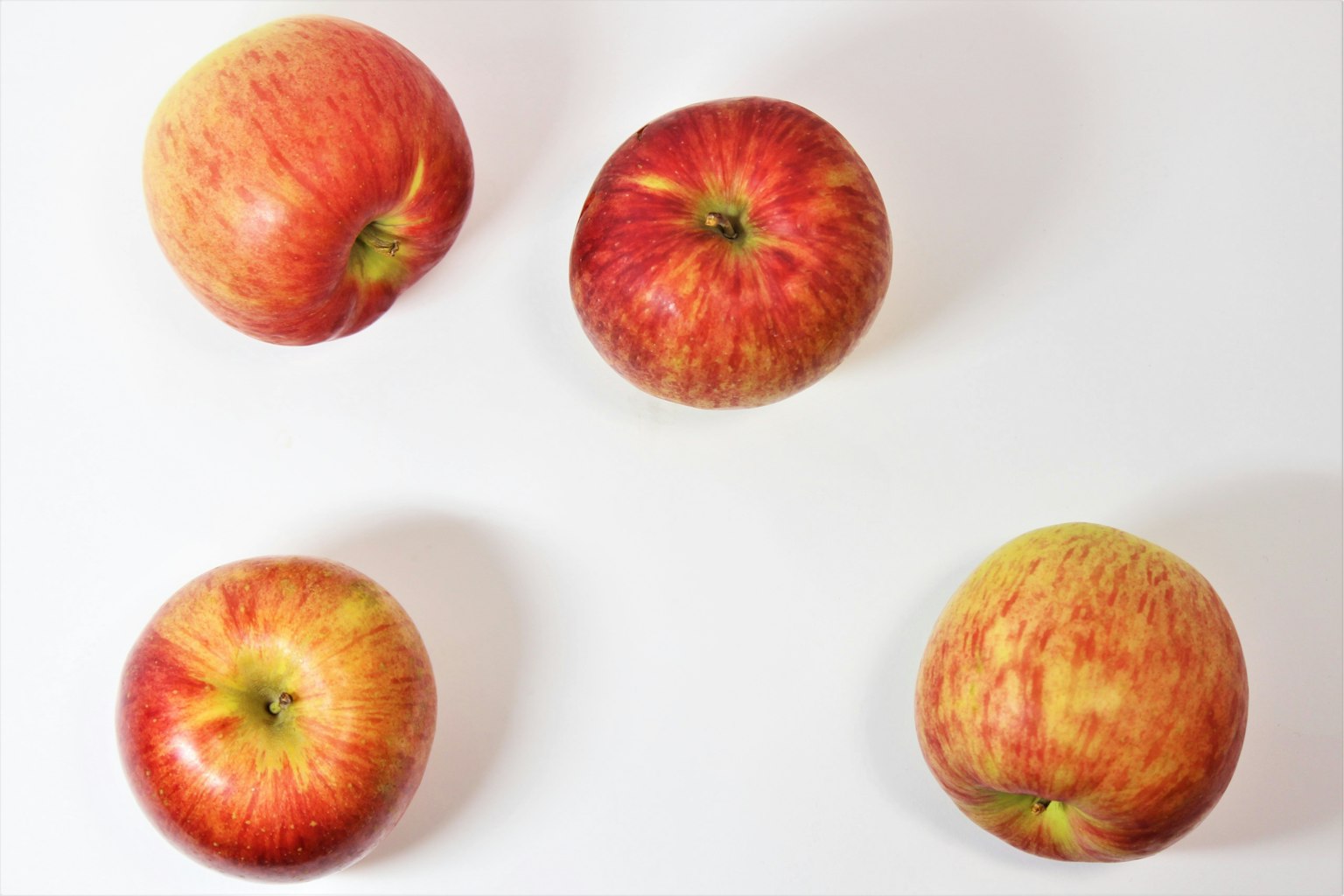 Quatre pommes rouges disposées sur un fond blanc