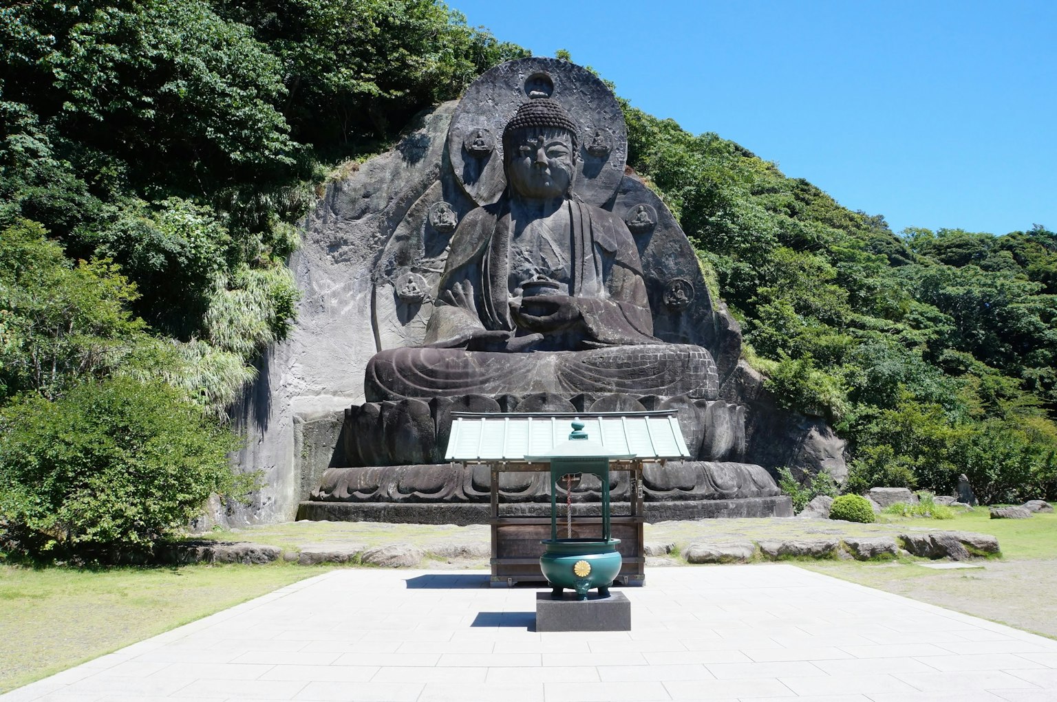 Large Buddha statue set against a lush green backdrop