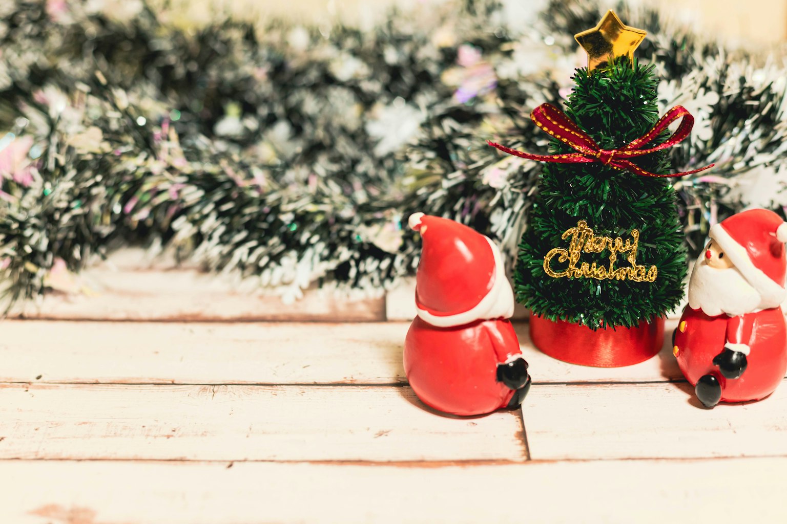 Adegan meriah dengan pohon Natal dan patung Santa di atas meja kayu