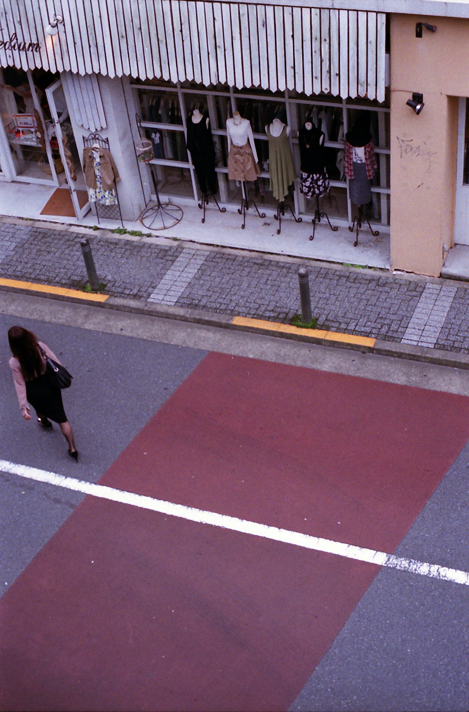 Une femme marchant sur un trottoir à rayures rouges avec des vitrines de magasin