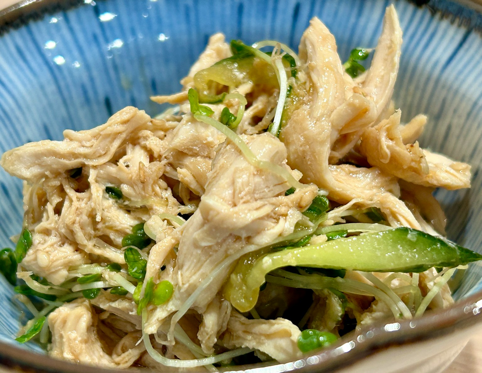 Shredded chicken salad with vegetables in a blue bowl