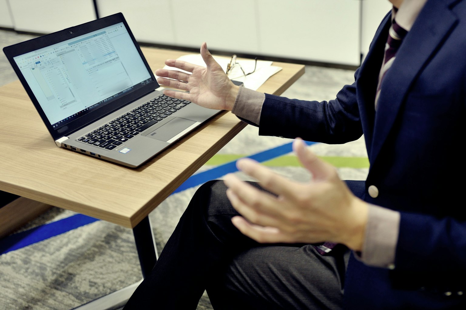 Ein Mann im Anzug, der vor einem Laptop gestikuliert