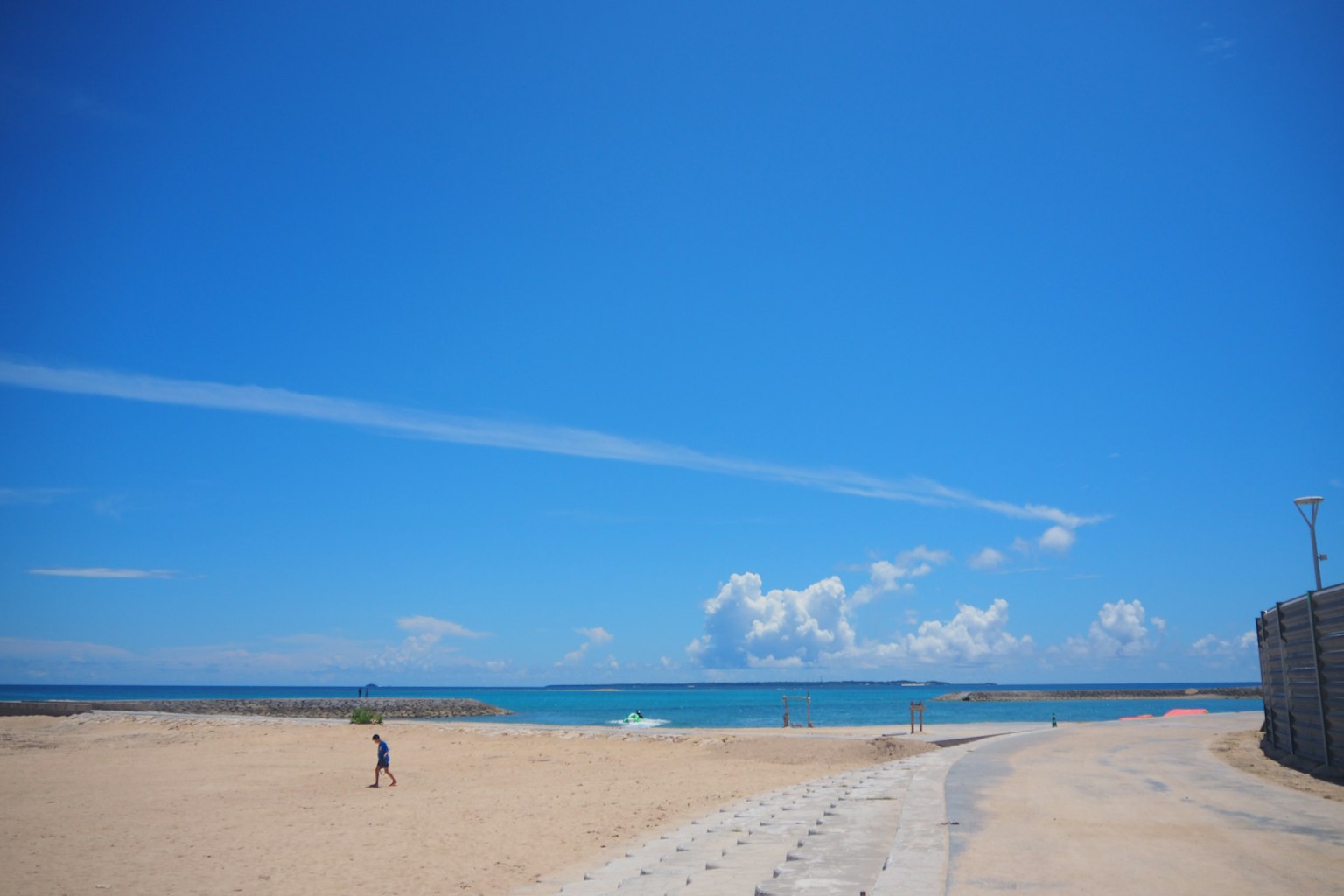 ทิวทัศน์ชายหาดที่มีท้องฟ้าสีฟ้าและมหาสมุทรผู้คนเดินอยู่บนชายหาด