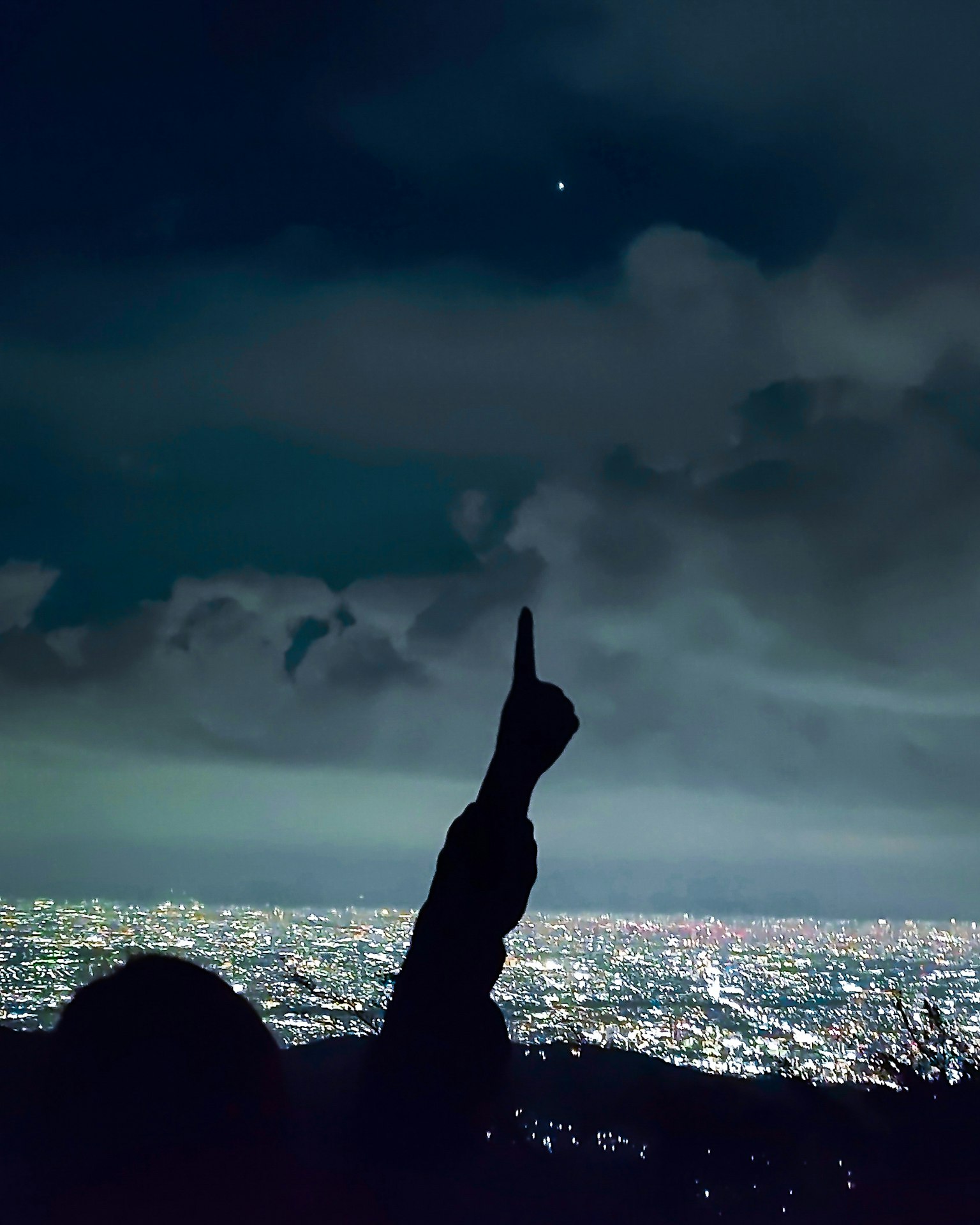 Silhouette d'une personne pointant une étoile sur fond de ville nocturne