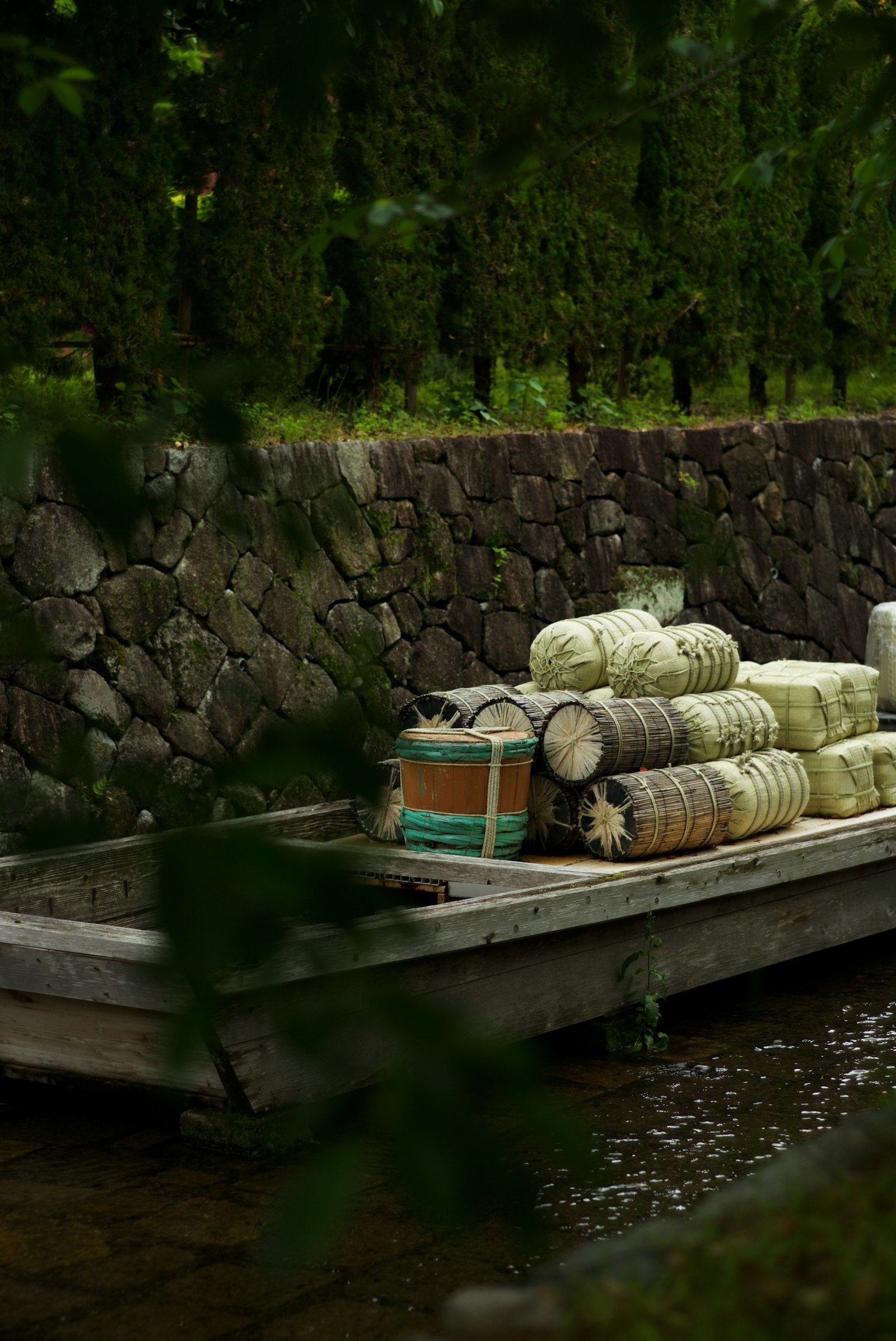 A small boat loaded with wooden barrels and bundles of straw