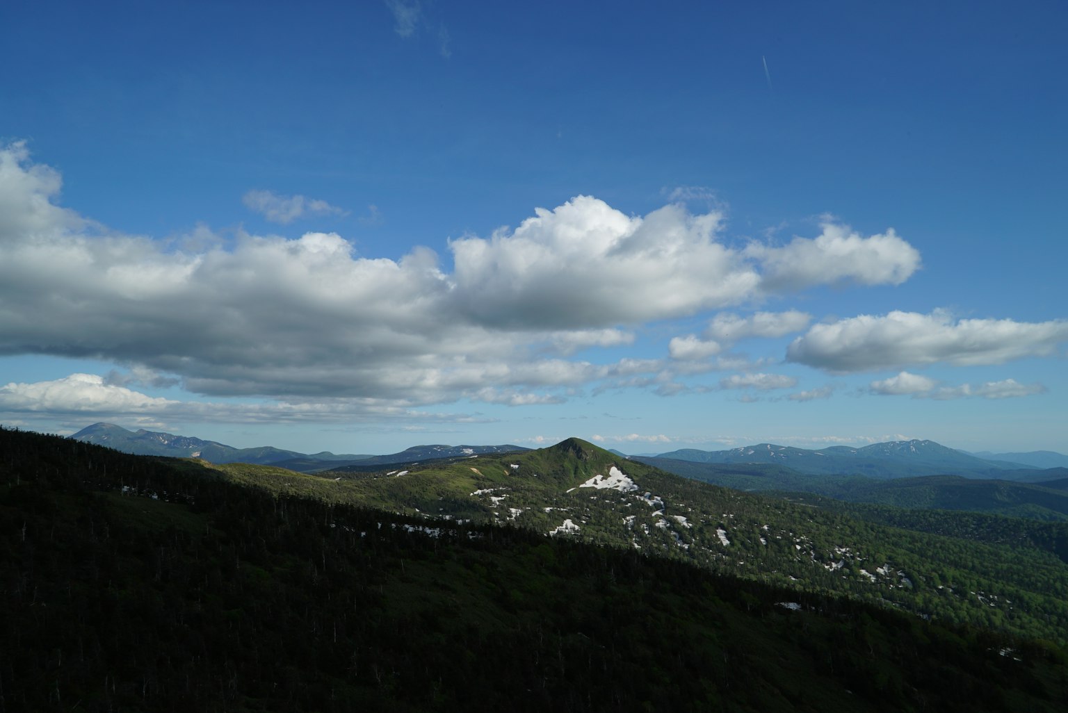 Mountain landscape with blue sky and white clouds green hills and distant mountains