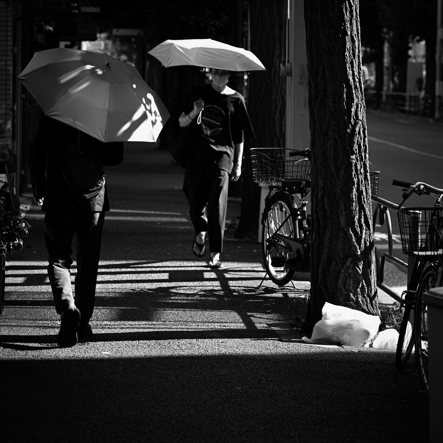 Due persone che camminano per strada con ombrelli