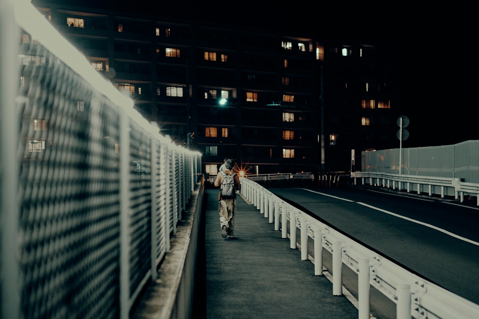 Una persona che cammina su un sentiero illuminato di notte con edifici sullo sfondo