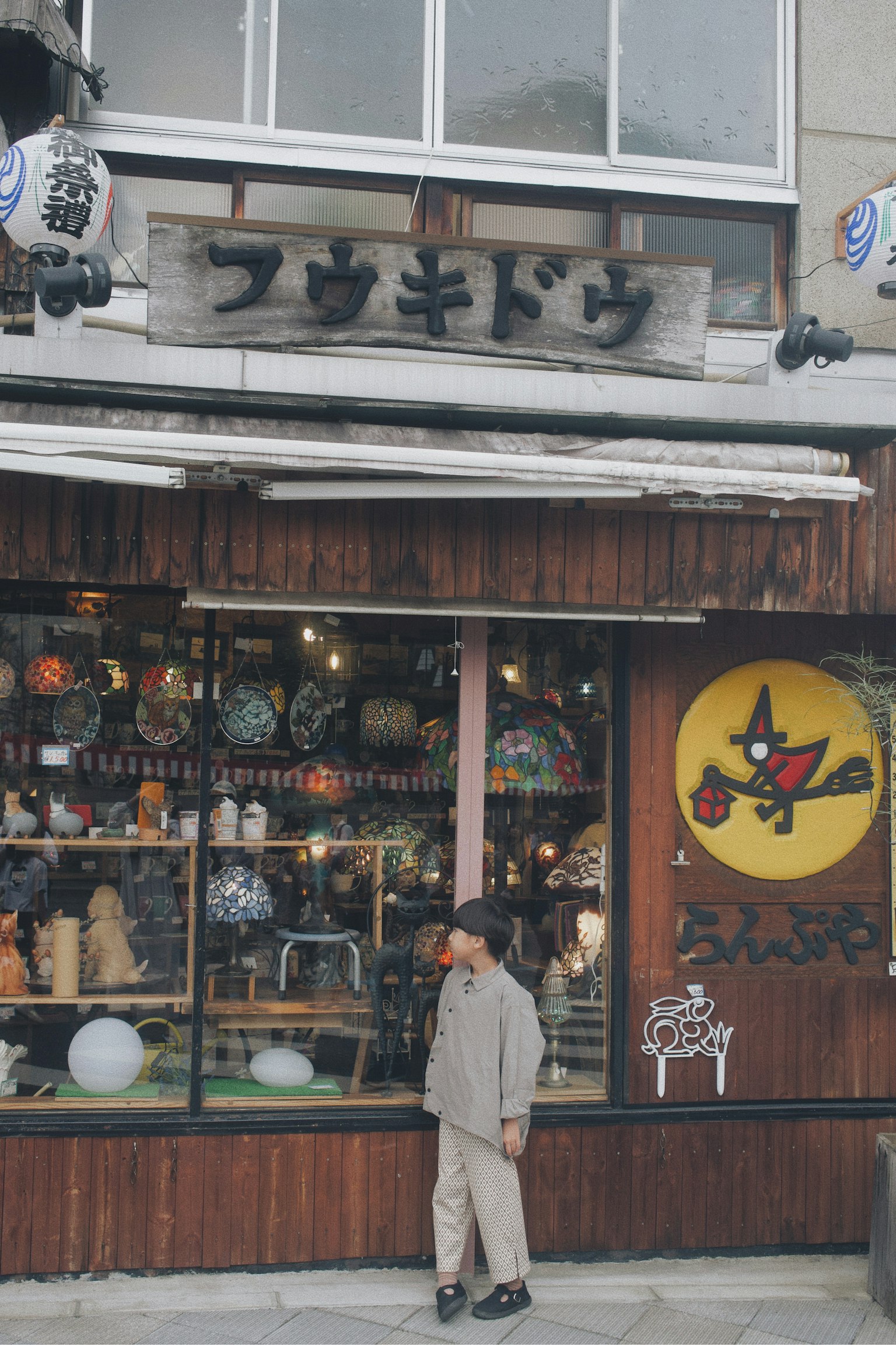 伝統的な店の前に立つ子供と色とりどりの装飾品