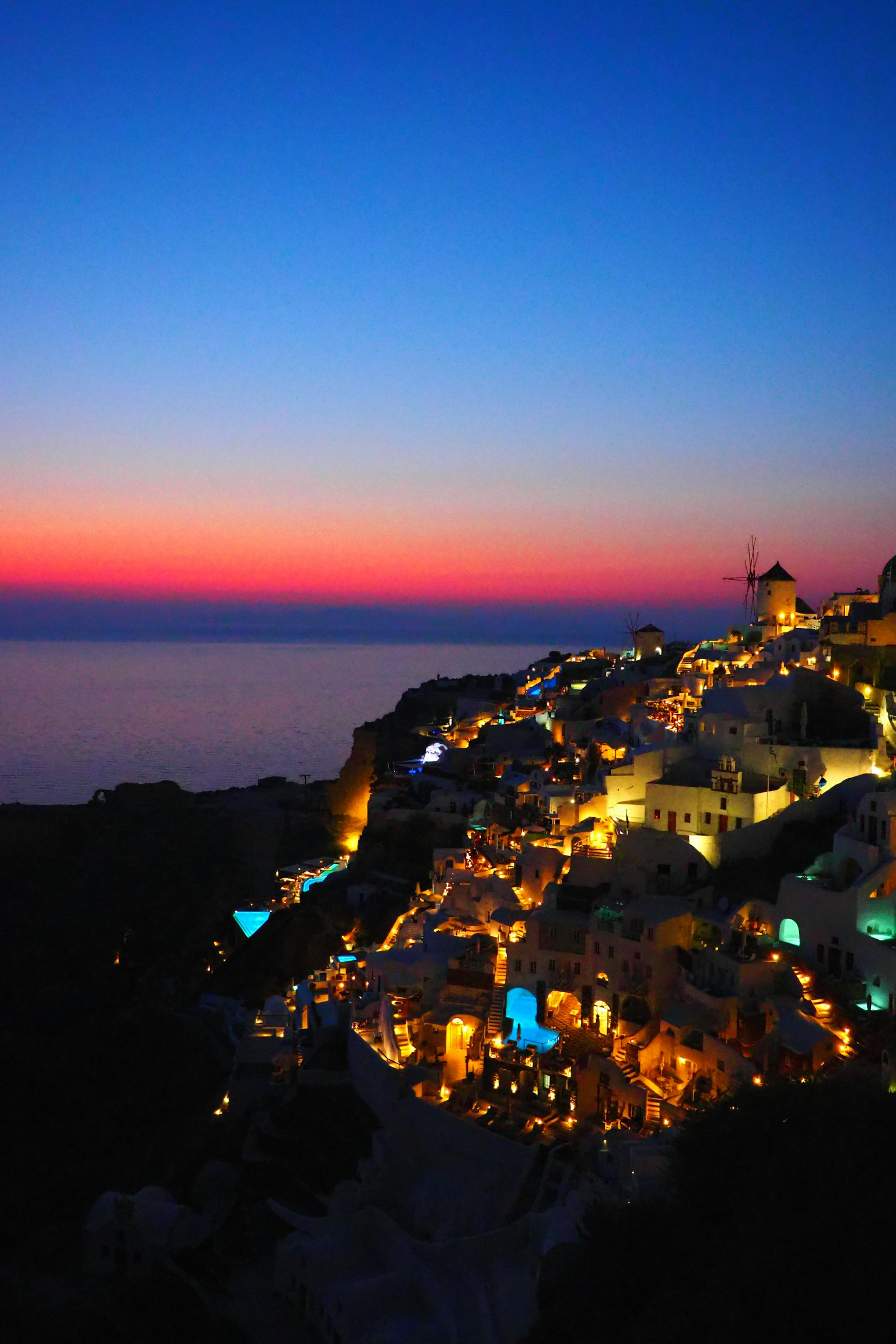 Case illuminate di Santorini contro un bellissimo cielo al tramonto e il mare