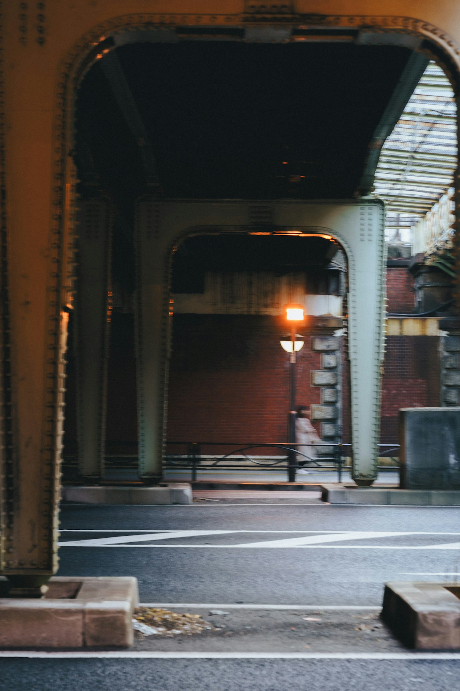 Städtische Szene mit einer Straßenlaterne und einem Fußgänger unter einer Brücke