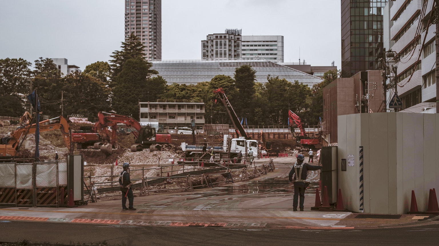 Site de construction avec grues et machines lourdes visibles