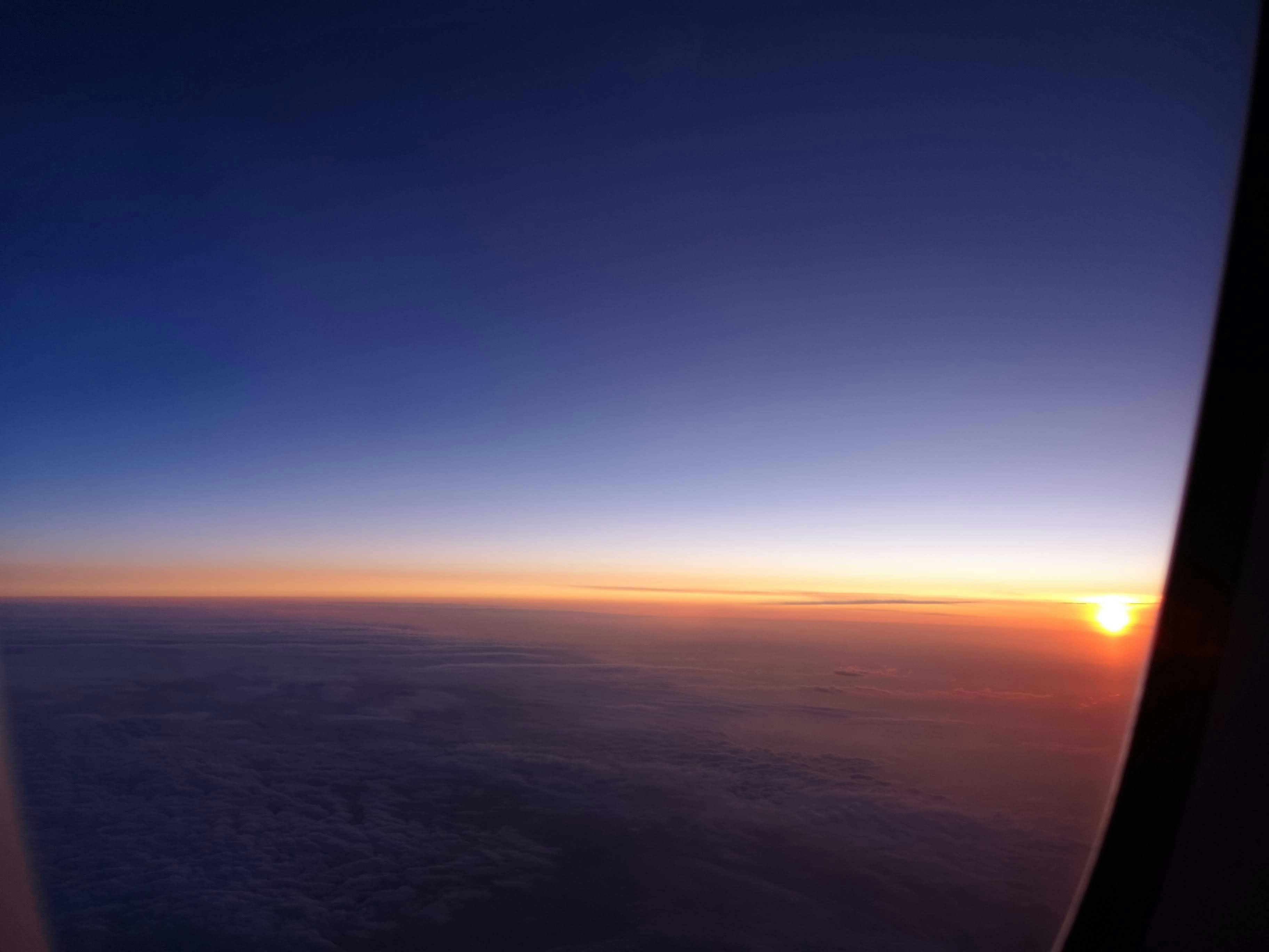 窓越しに見える夕焼けの空と広がる地平線