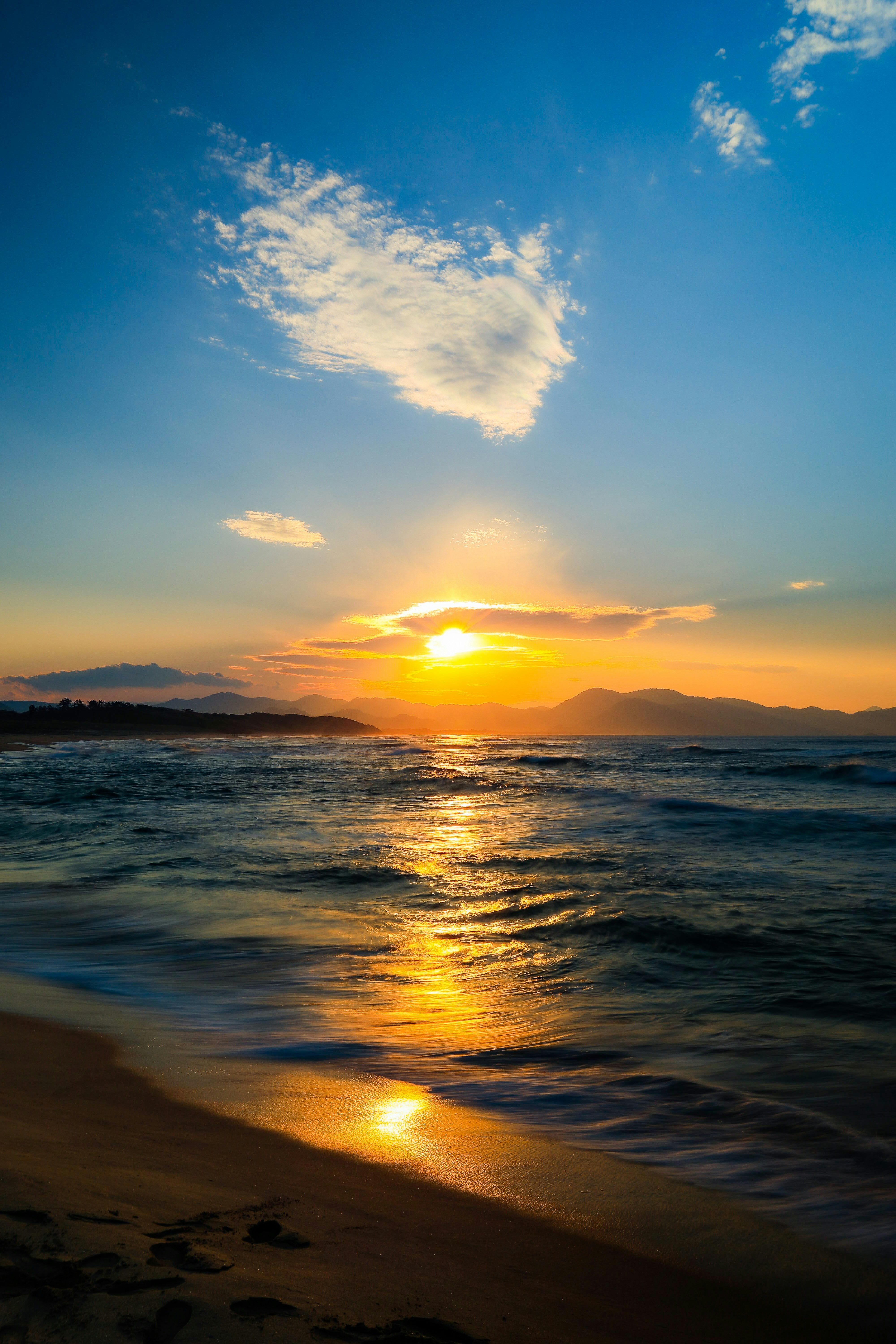 夕日に照らされた海辺の波と砂浜の風景